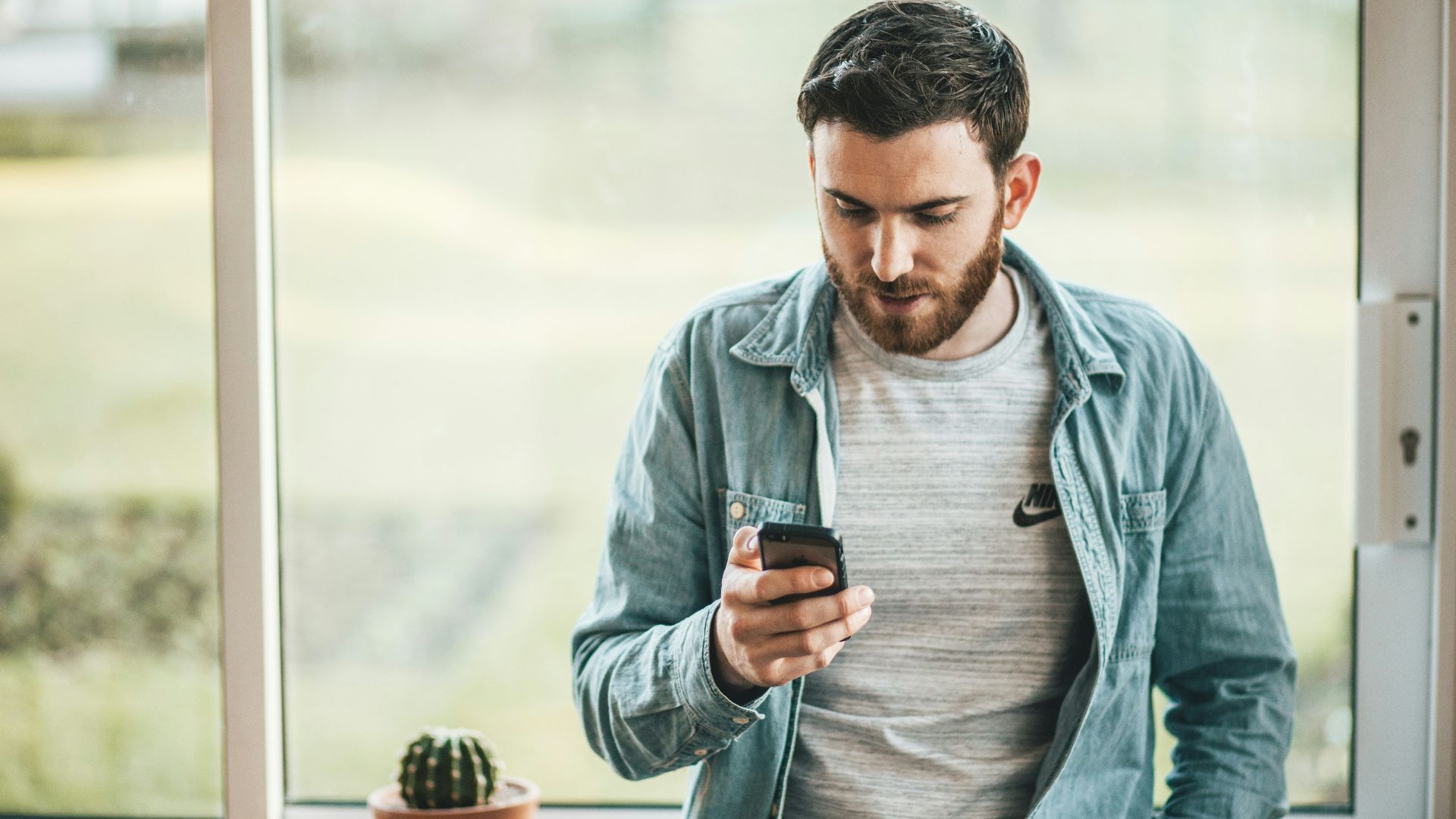 man holding a smartphone near the window