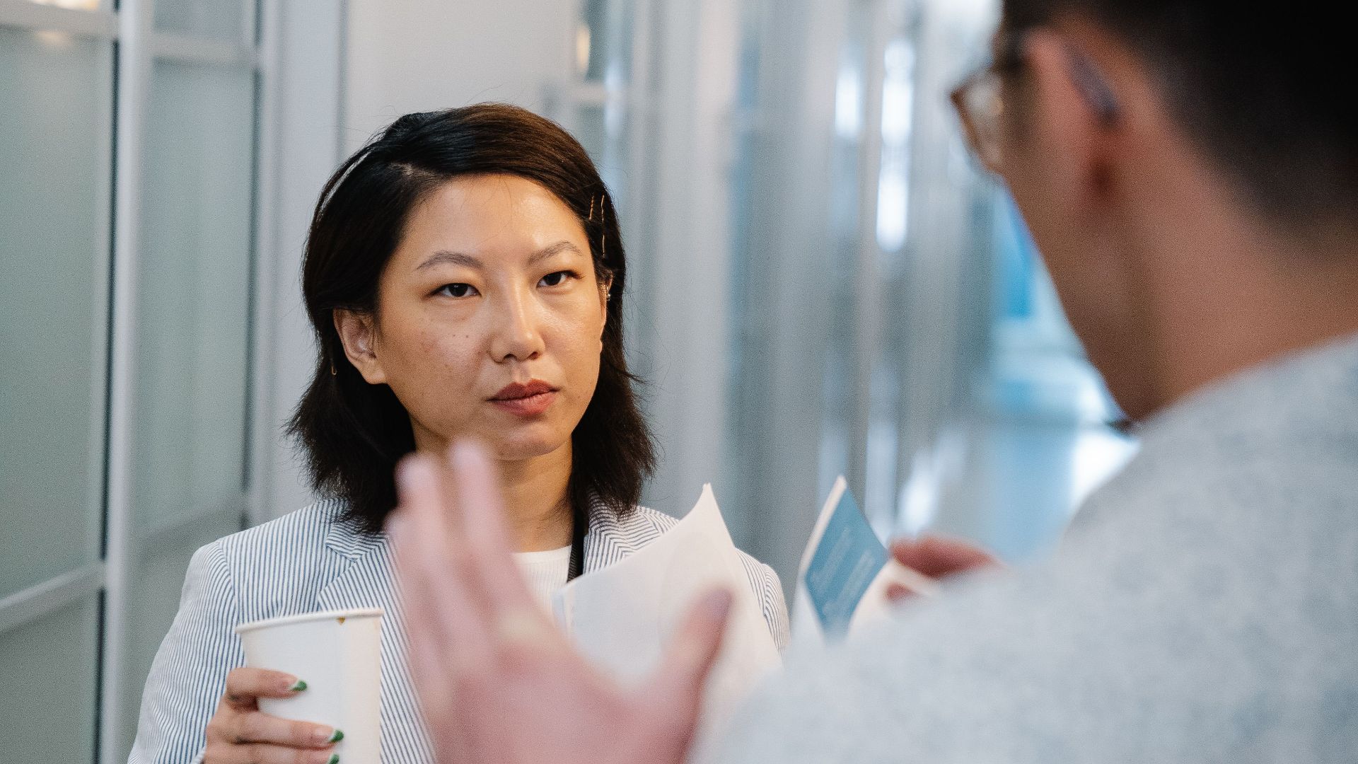 A man and woman having a conversation in a modern office hallway.