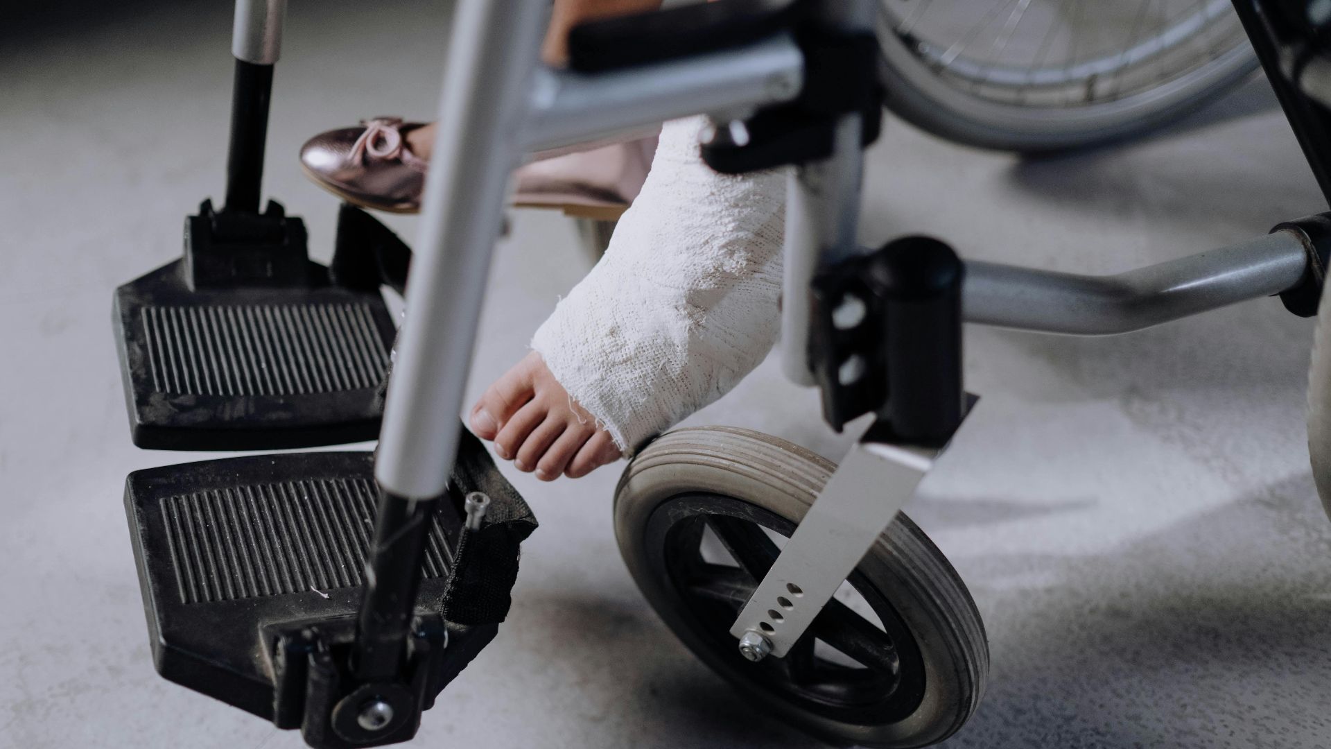 Close-up of an injured foot in a cast resting on a wheelchair, indoors.