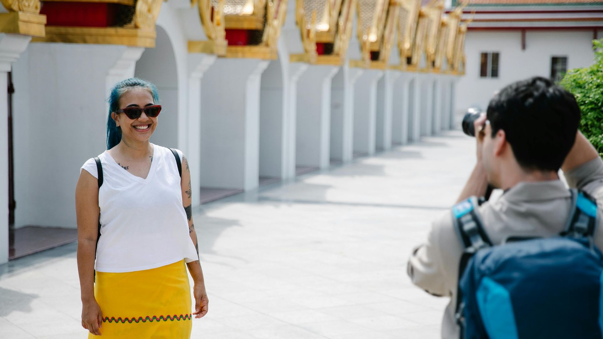 Woman posing for a photo at a temple with golden architecture, capturing a travel moment.
