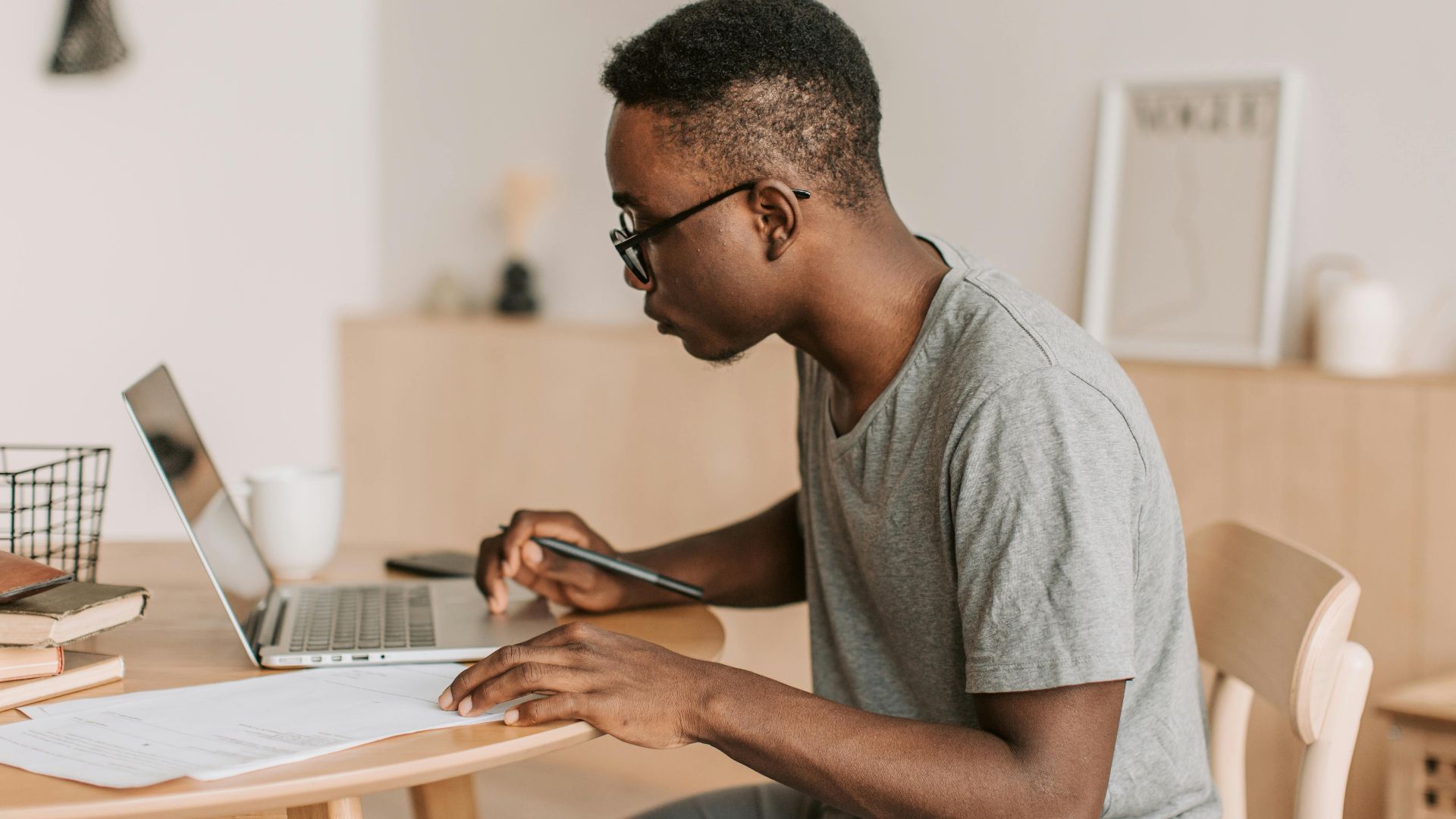 Young man working remotely on a laptop indoors, using digital tools for communication.