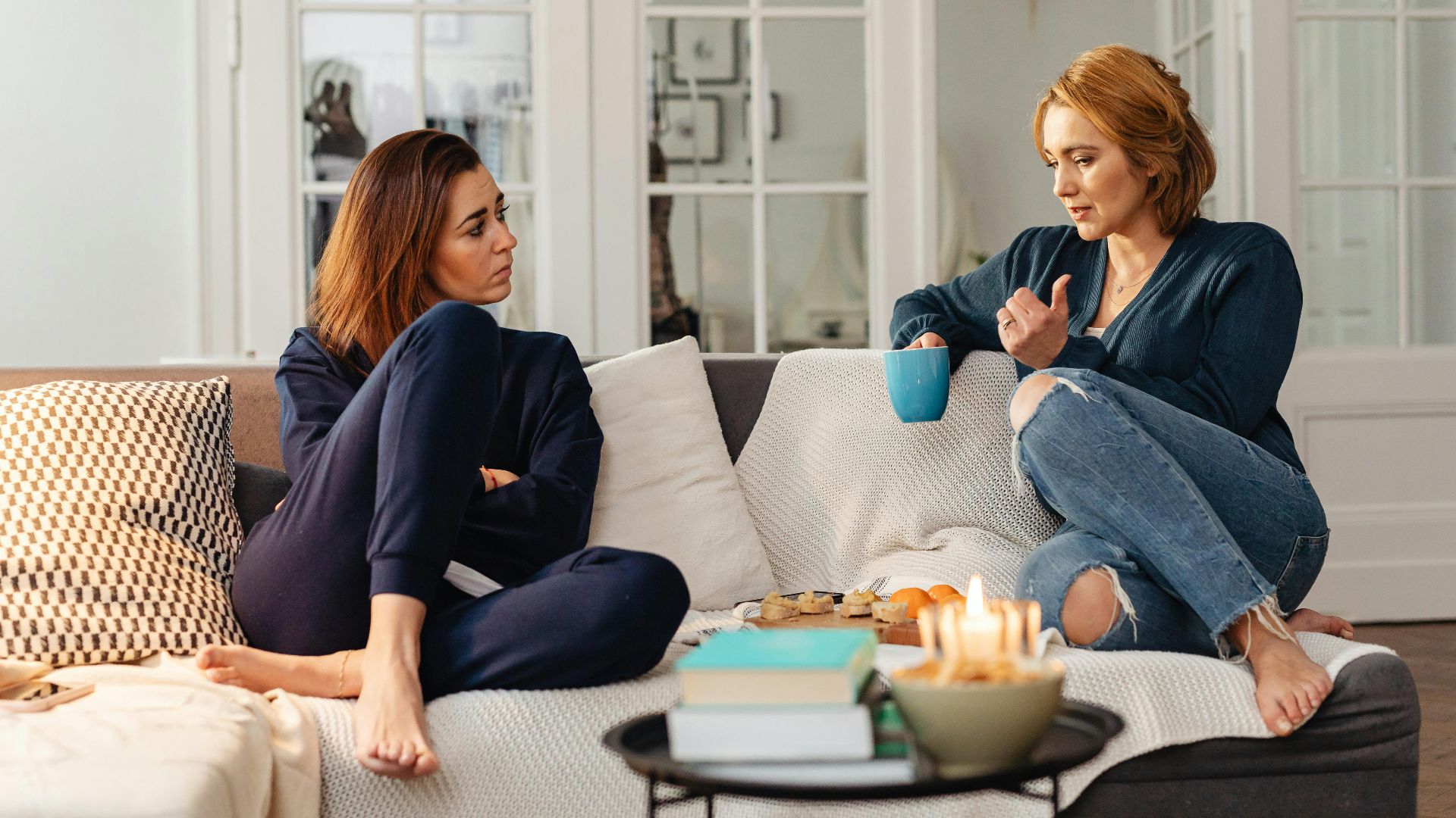 Two women having a heartfelt conversation, enjoying a cozy moment in a modern living room.