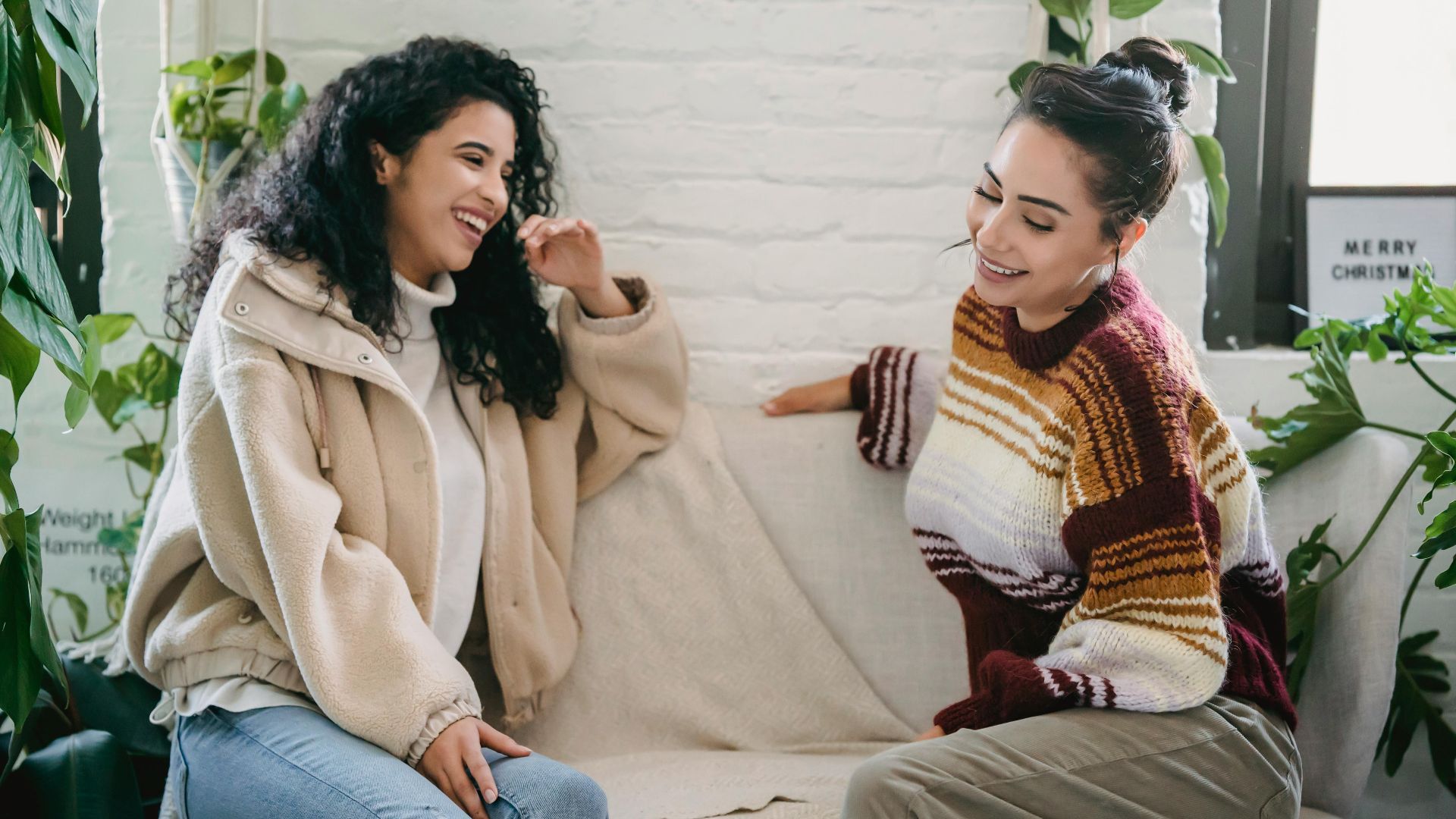 Side view of young woman in casual clothes sitting on sofa and talking while spending weekend together