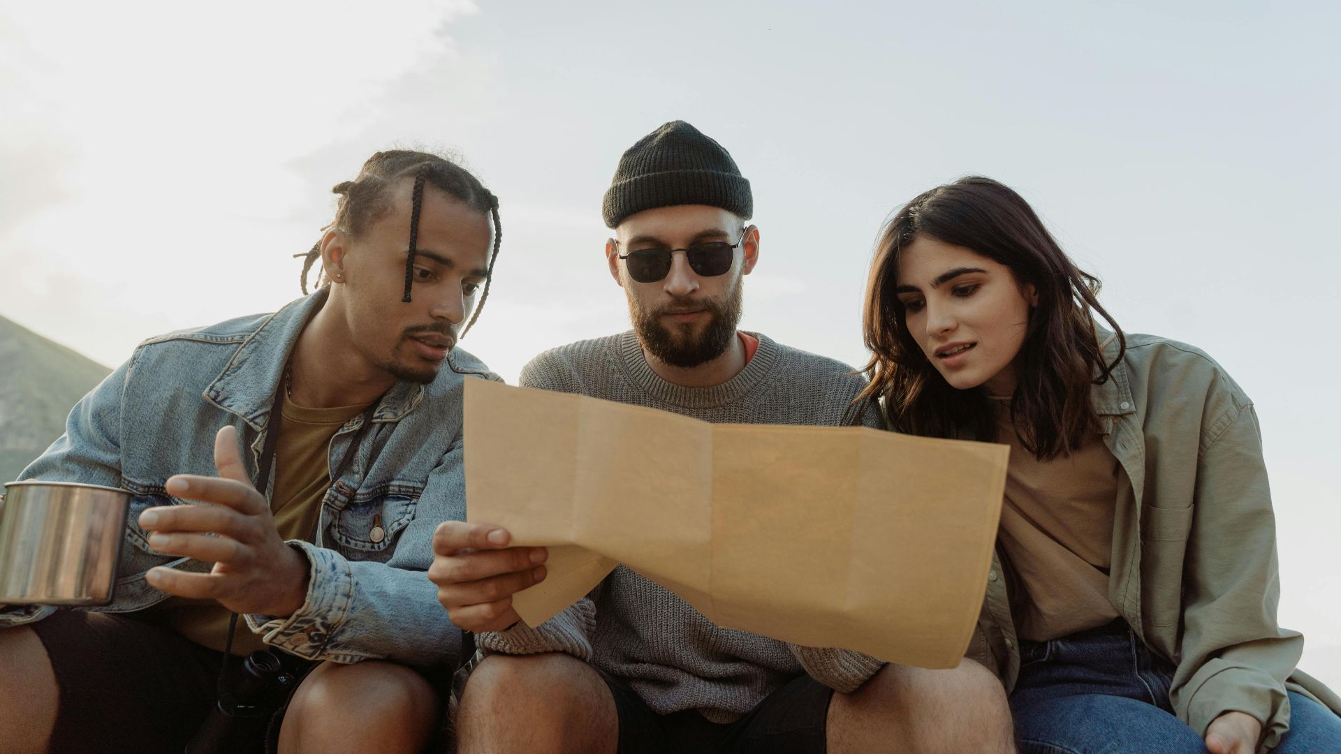 Group of diverse friends reading a map outdoors, exploring and planning their adventure.