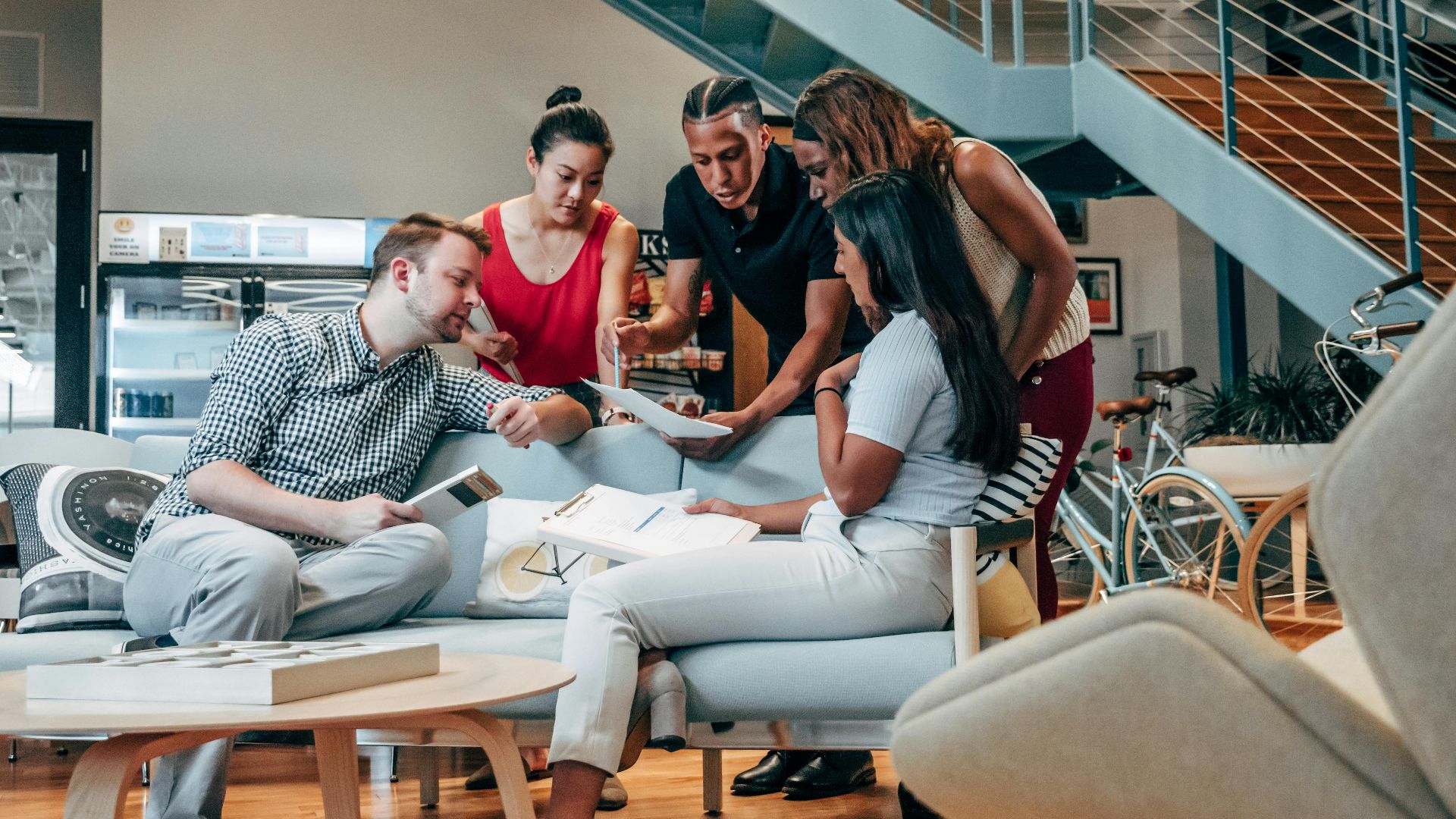 A diverse group of coworkers engaged in brainstorming and planning in a modern office lobby.