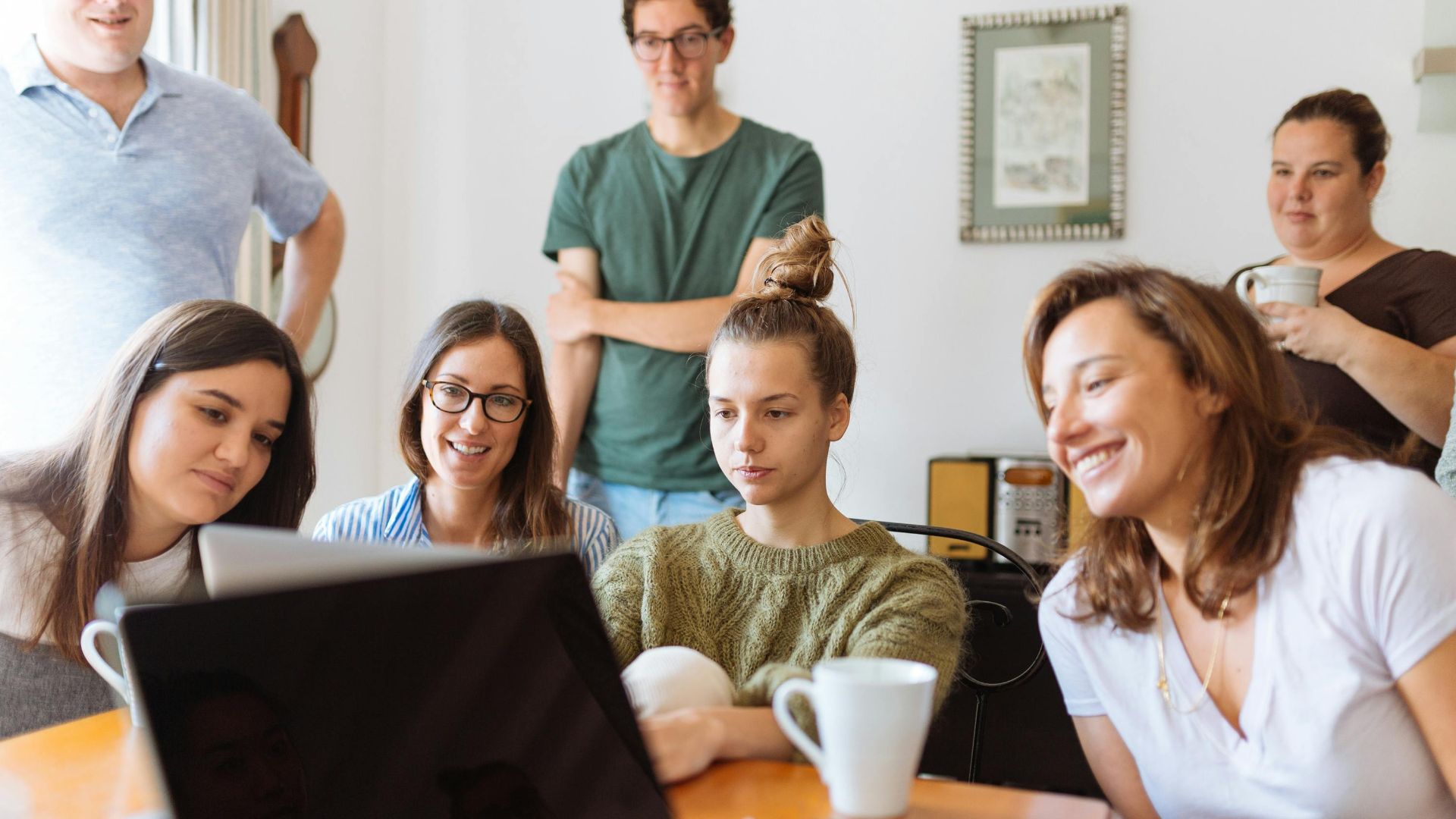 A diverse group of adults at work, enjoying a casual meeting indoors with focus and smiles.