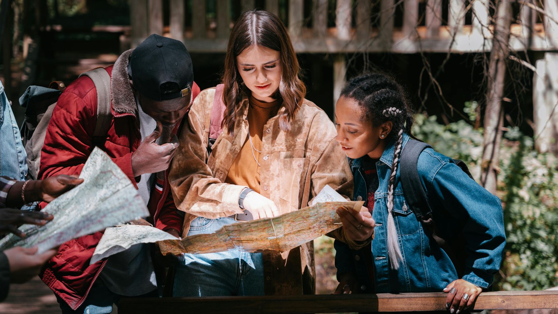 A group of young friends studying a map outdoors, planning an adventure.
