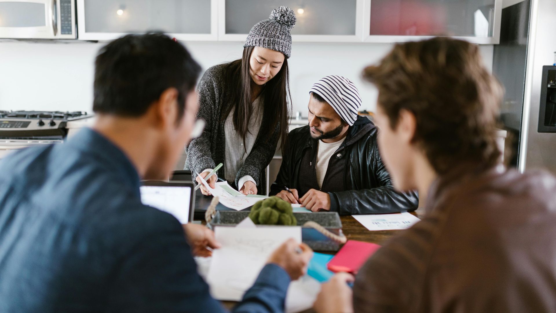 A dynamic group of young entrepreneurs brainstorming in a well-lit office space.