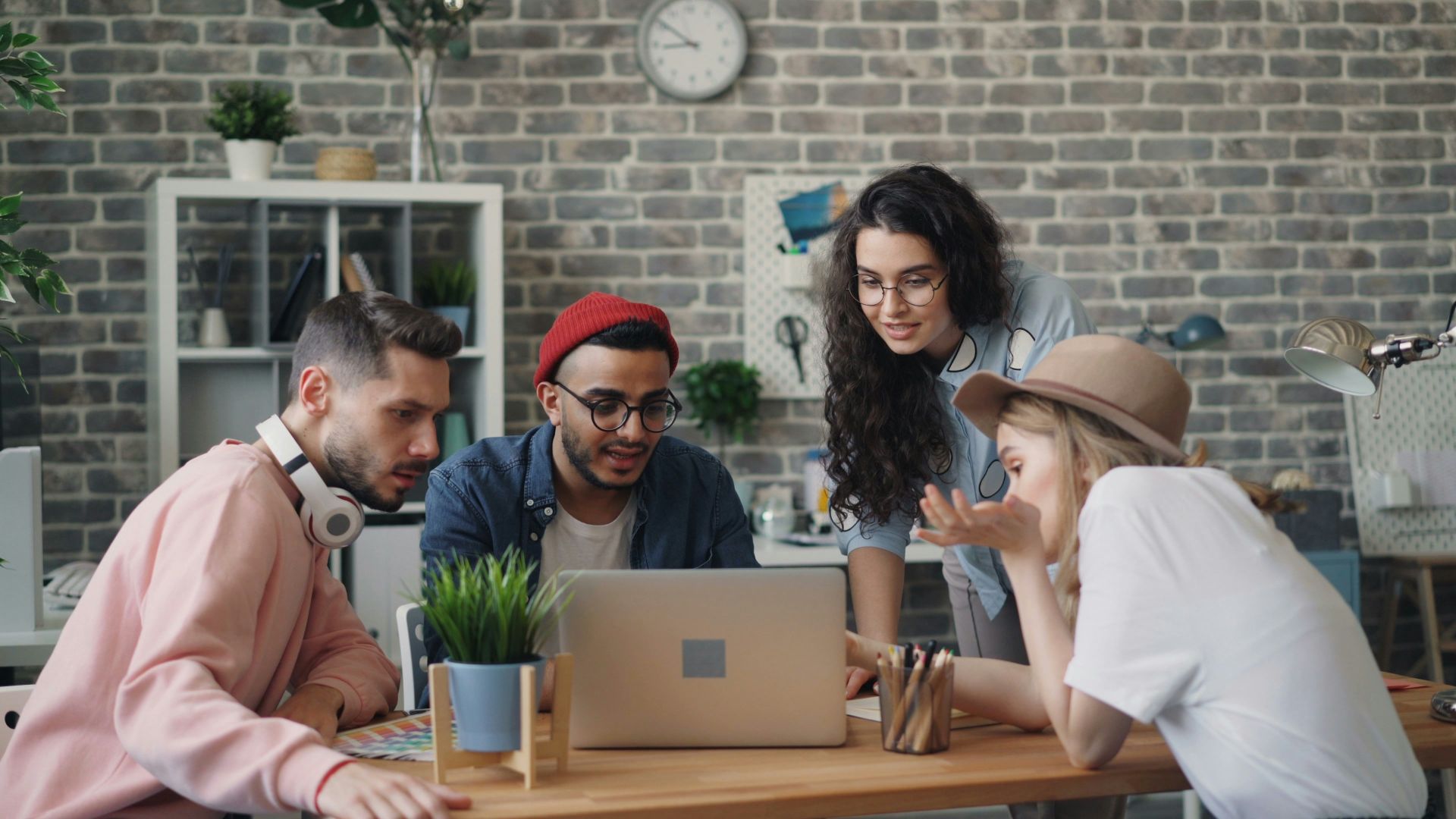 a group of people sitting around a table looking at a laptop