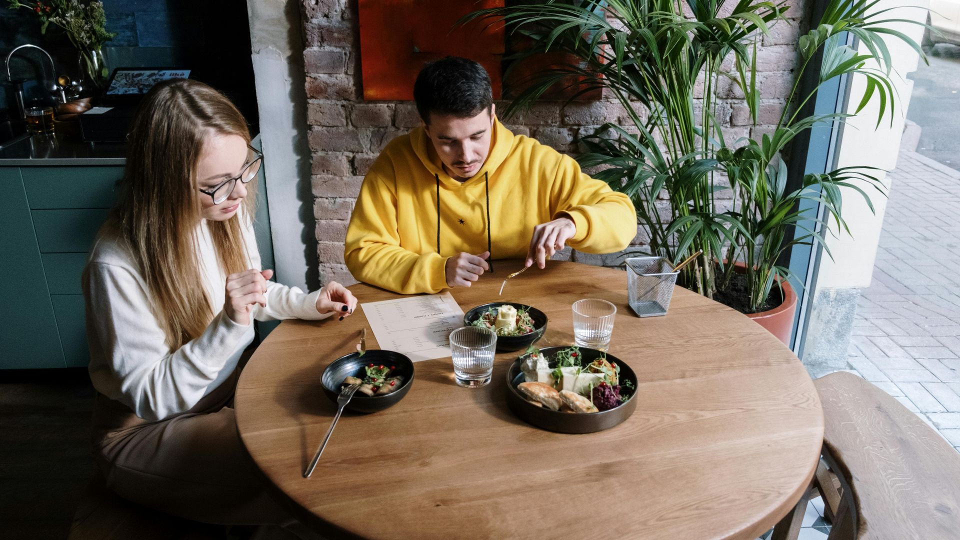A young couple enjoys a casual meal at a modern indoor restaurant setting.