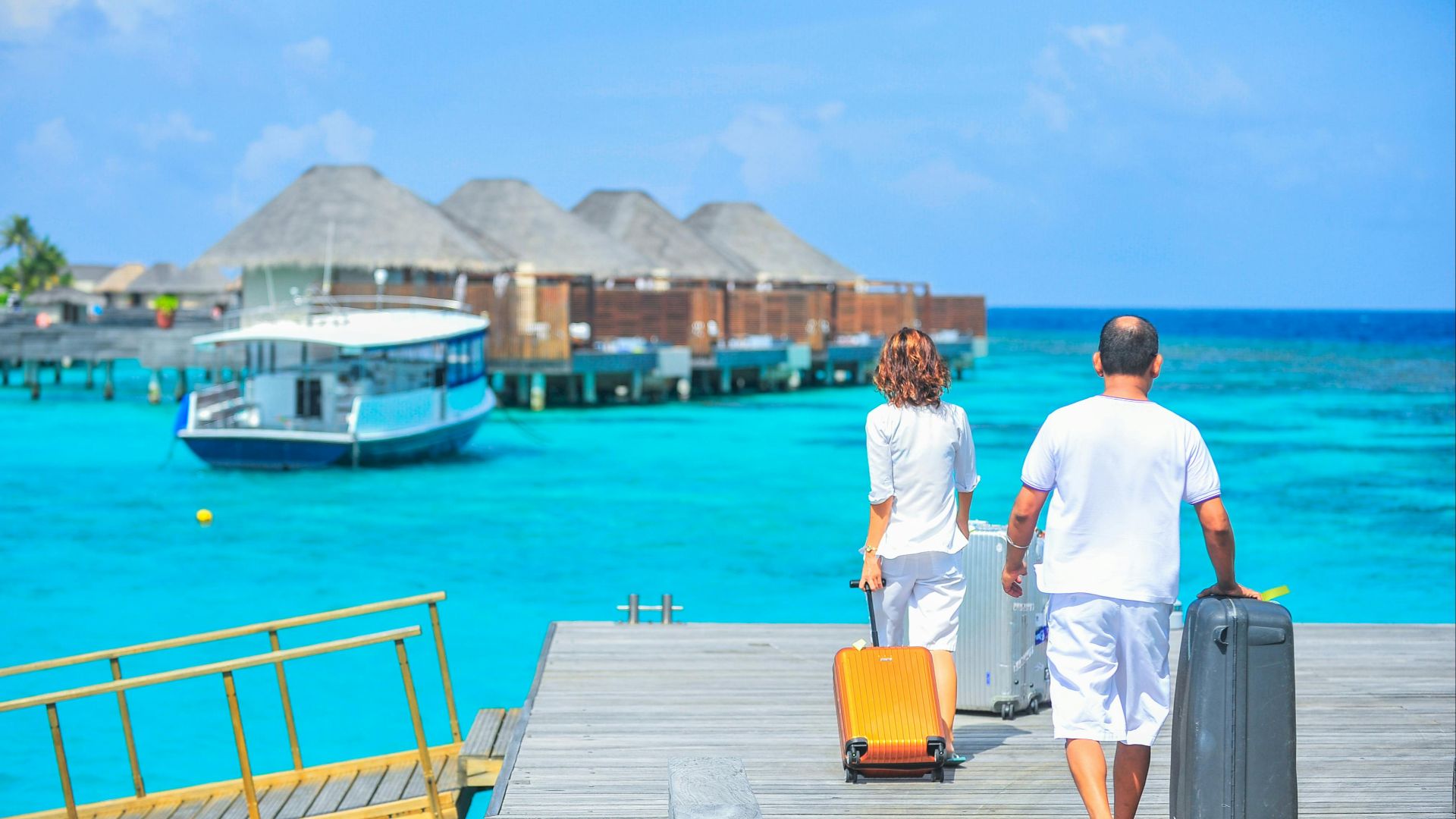 A couple arriving at a luxurious Maldives resort dock with luggage, capturing a tropical vacation vibe.