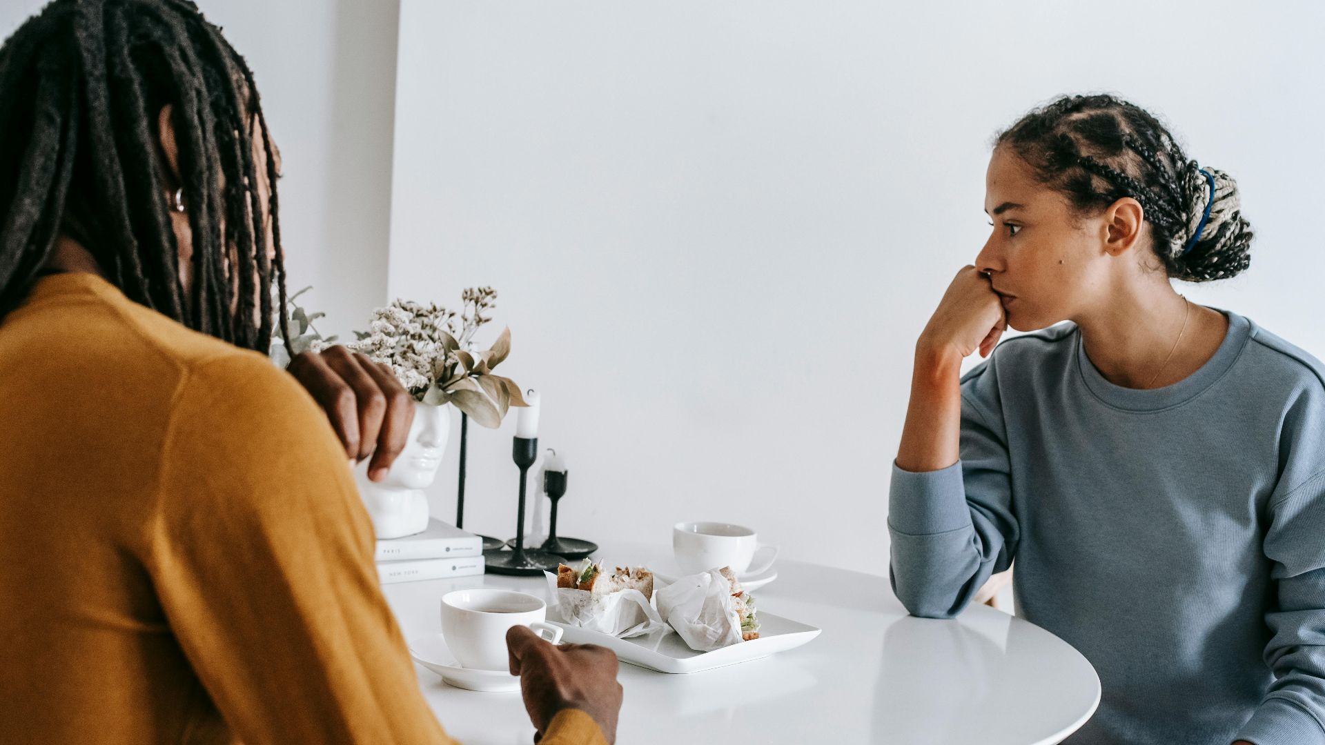 Young African American man sitting with woman at table and having conflict with each other at home