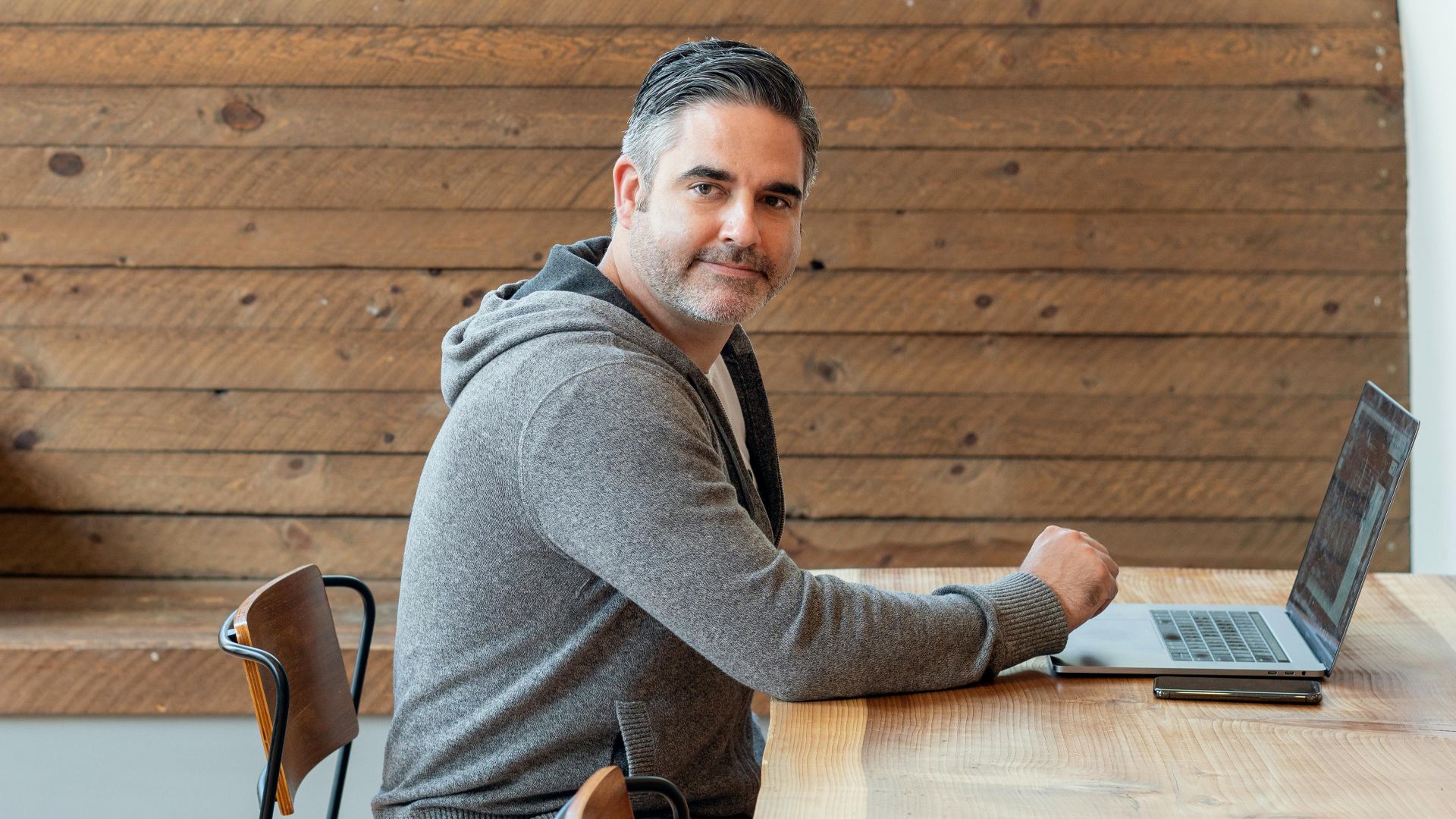 Adult man working on a laptop in a stylish coffee shop setting, ideal for remote work themes.