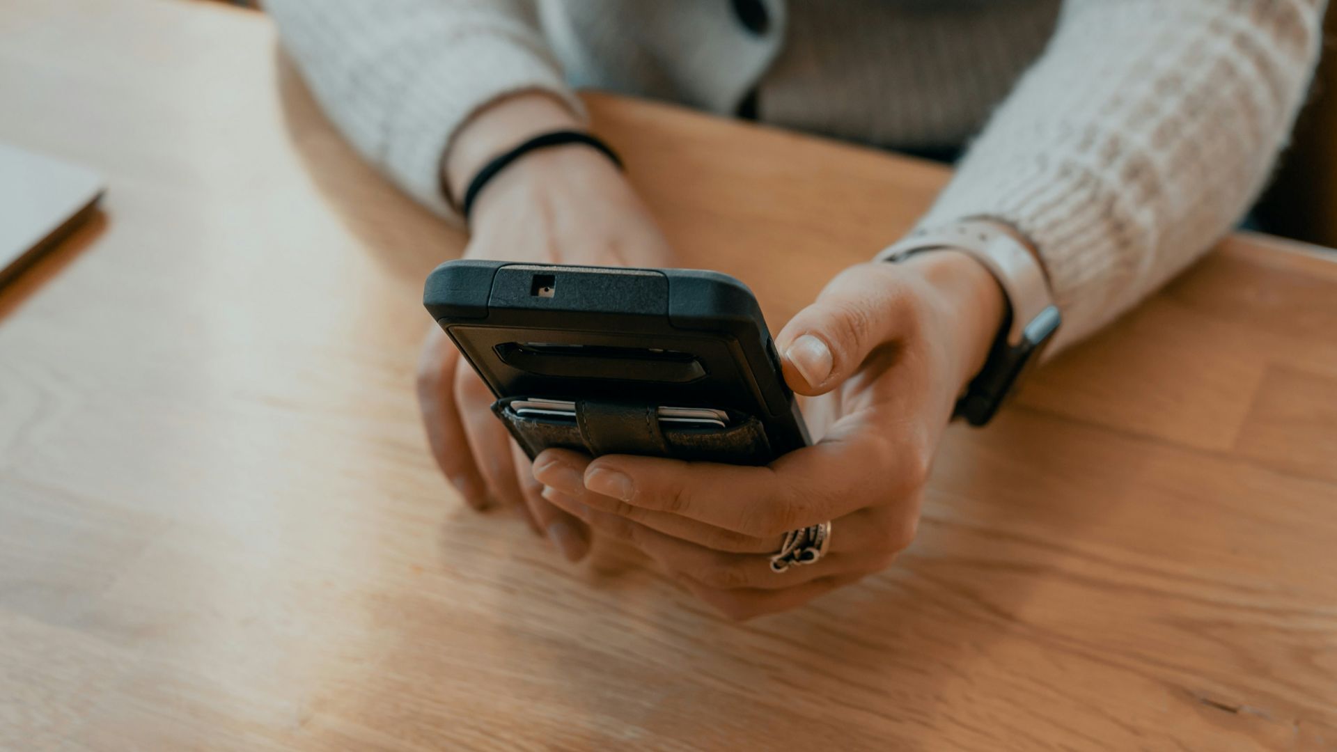 woman in white sweater holding black smartphone