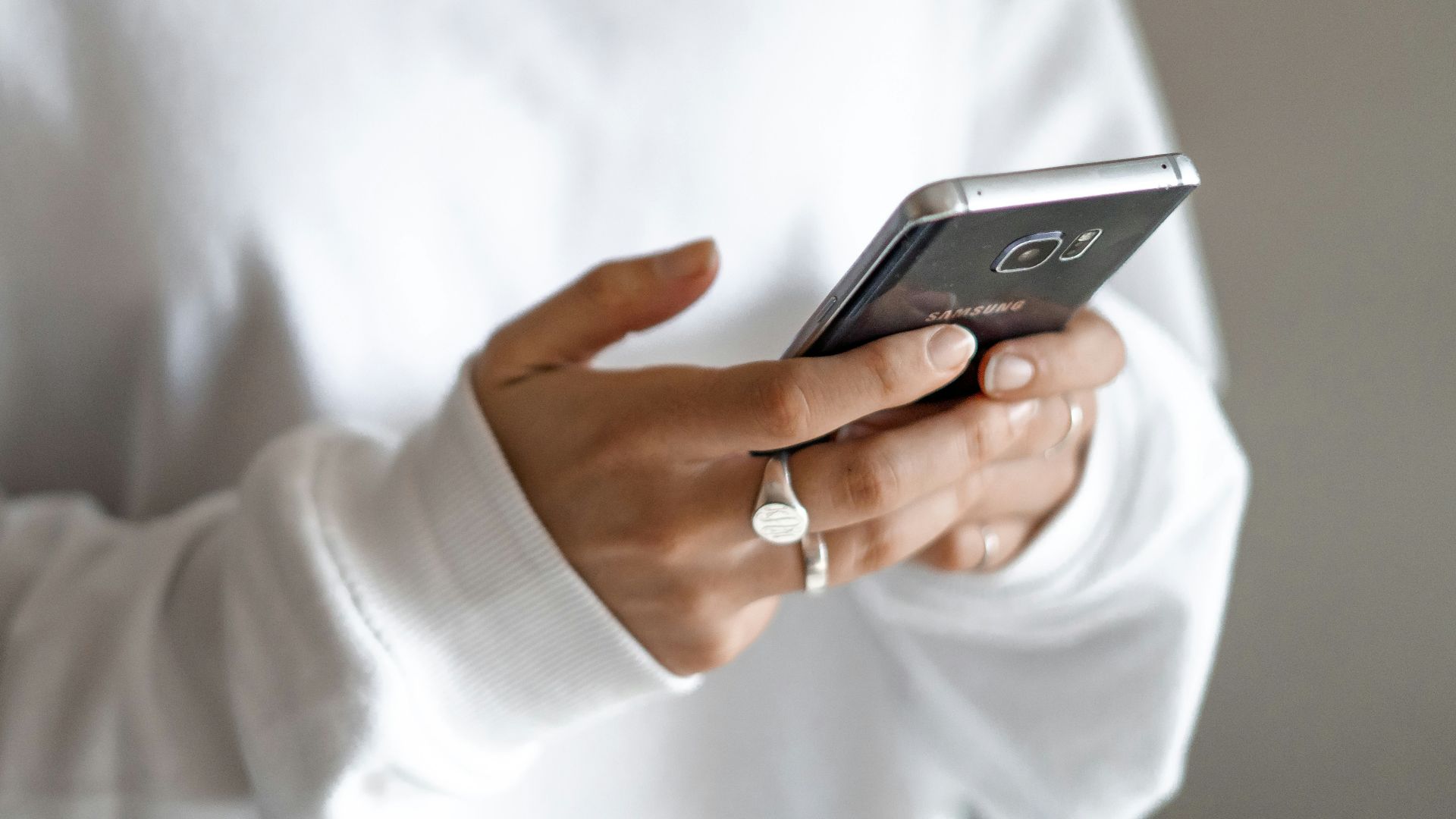 person in white long sleeve shirt holding black smartphone