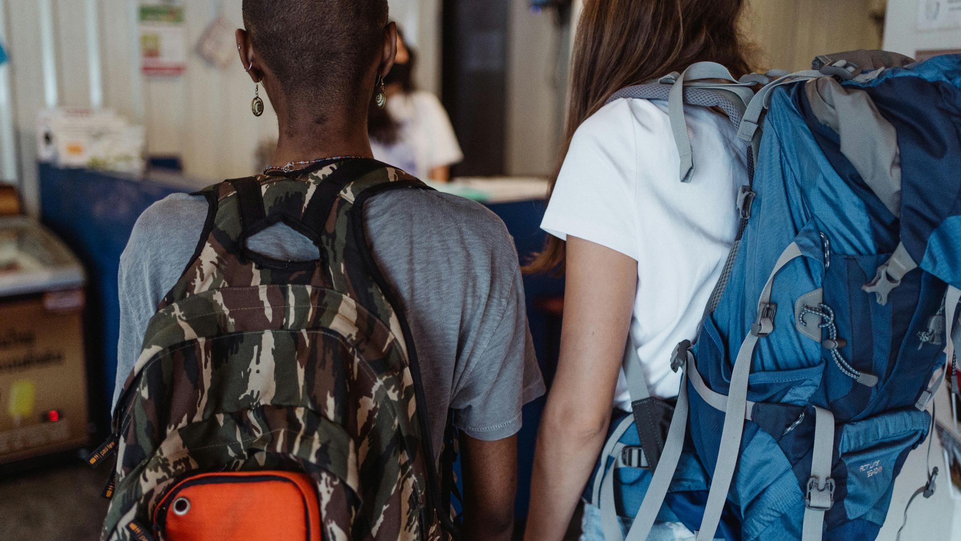 Two tourists with backpacks exploring indoors. Casual travel style.