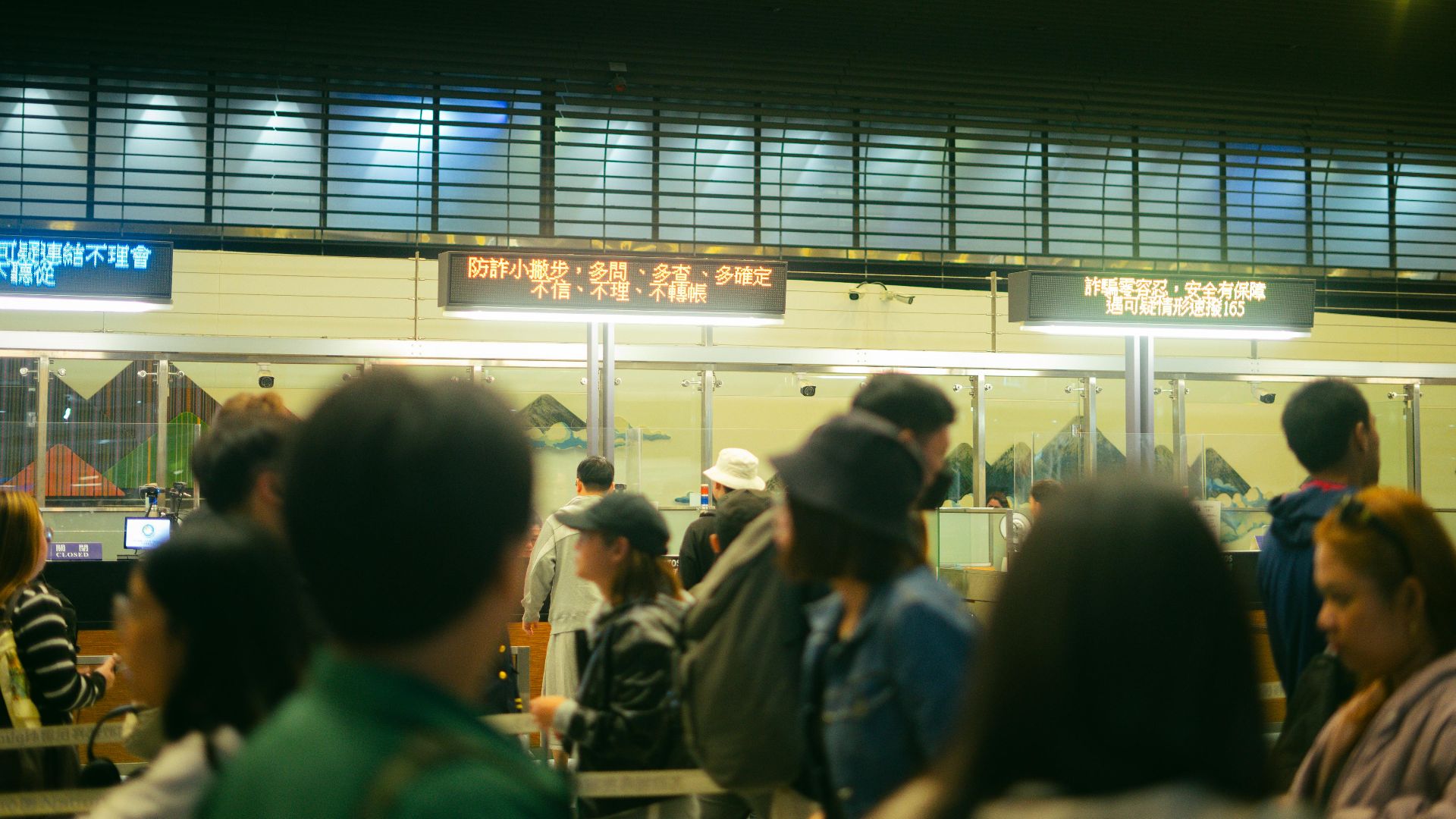 Crowded airport check-in area with people queueing and visible flight information signs.