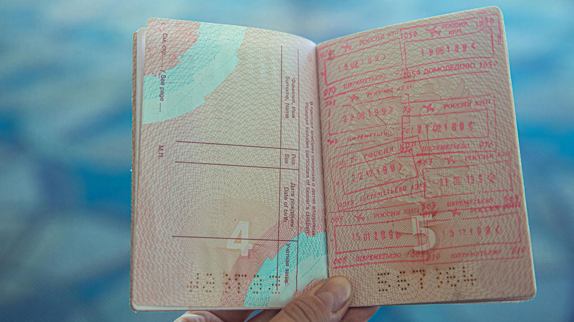 Close-up view of an open passport displaying various travel stamps in an airport setting.
