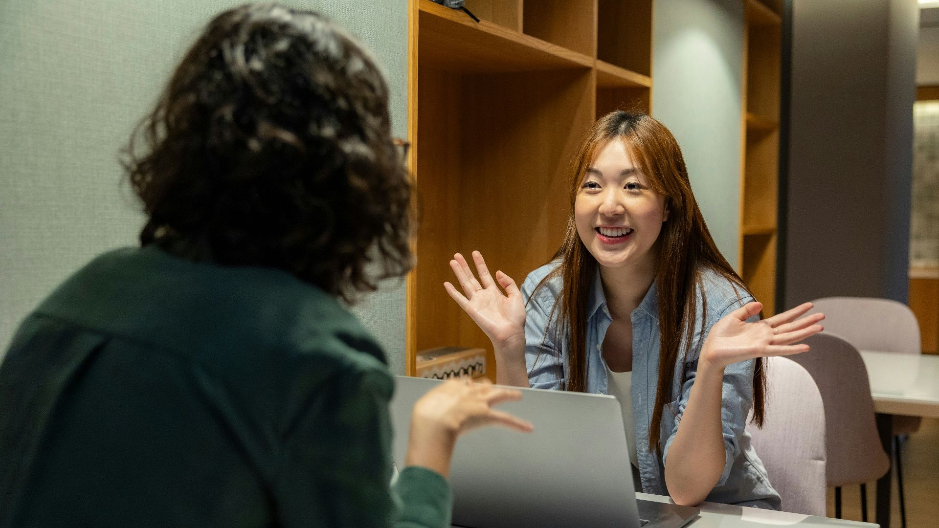 a woman sitting at a table talking to another woman