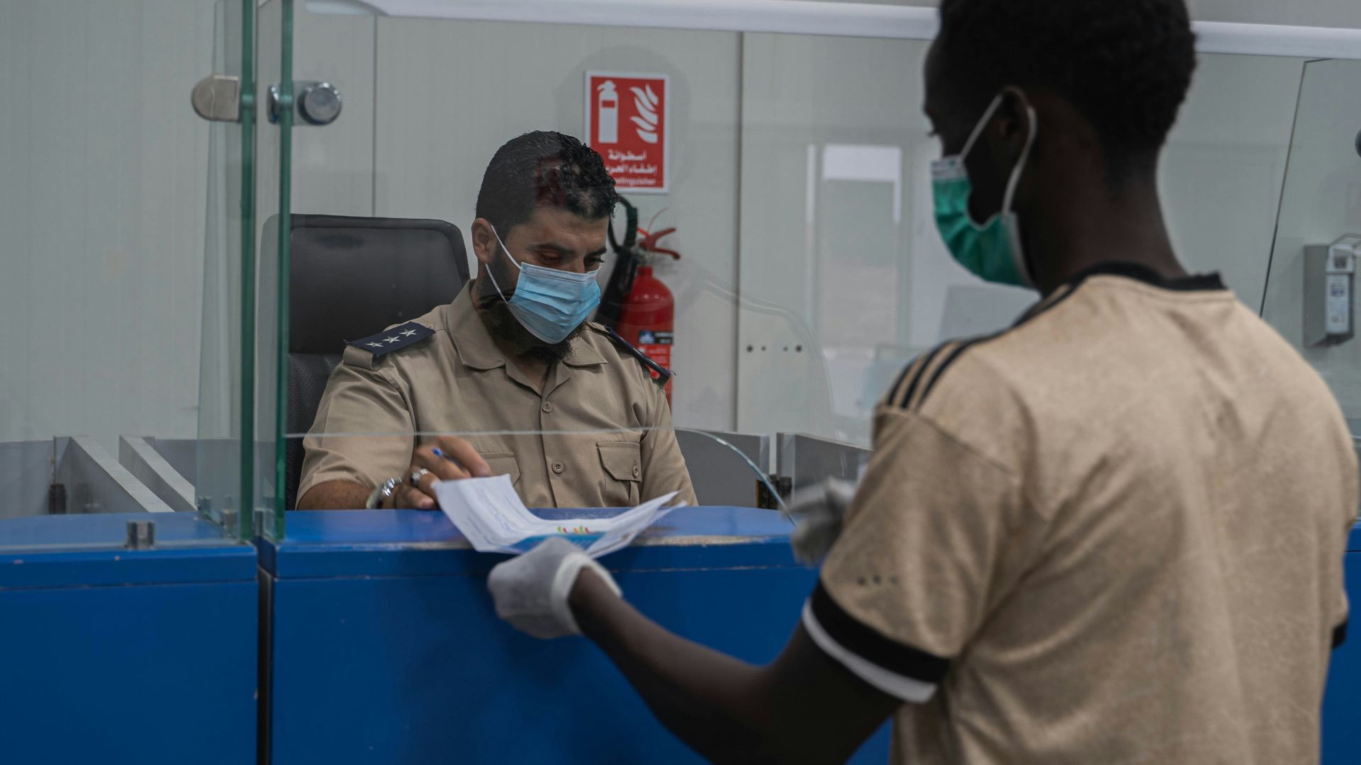 a man wearing a face mask and gloves standing in front of a counter