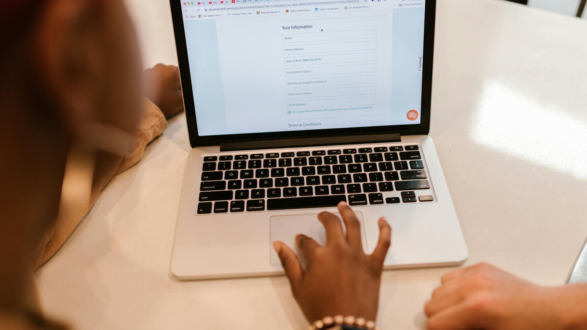 Two adults working together on a laptop displaying an online form, indoors.