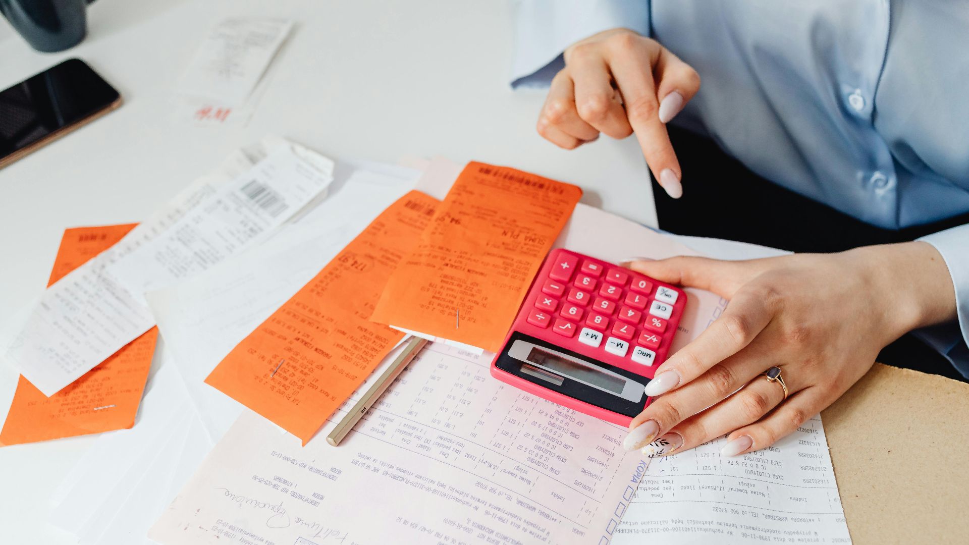 Businesswoman calculates expenses using receipts and calculator at desk. Ideal for finance, accounting themes.