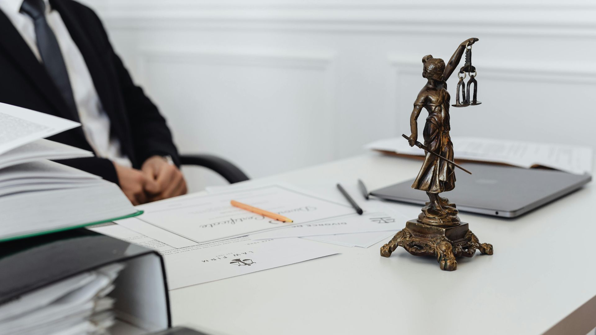 A legal professional's workspace featuring Lady Justice statue, documents, and a laptop.