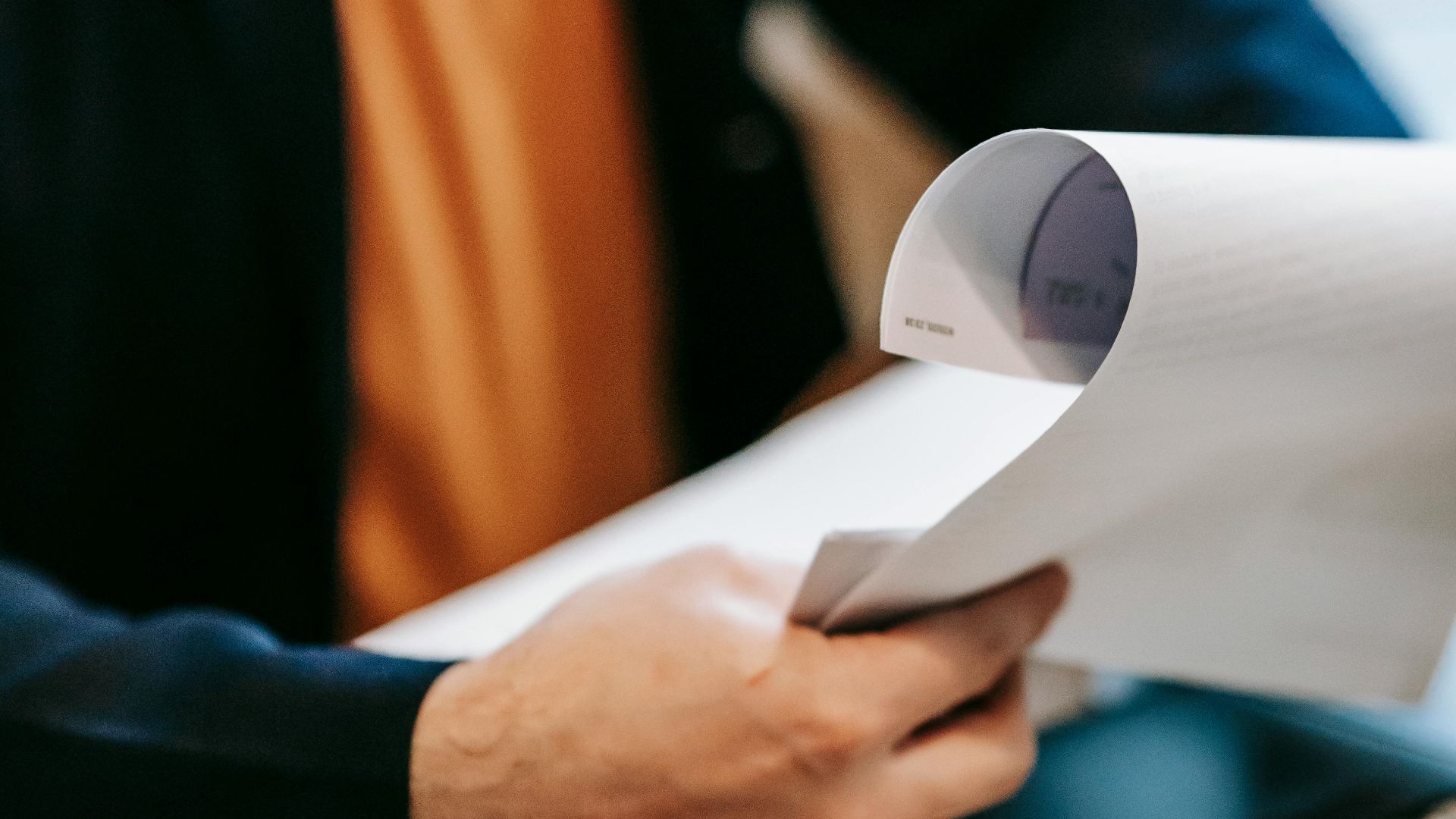 Business professional reviewing important documents indoors. Hands focus, blurred background.