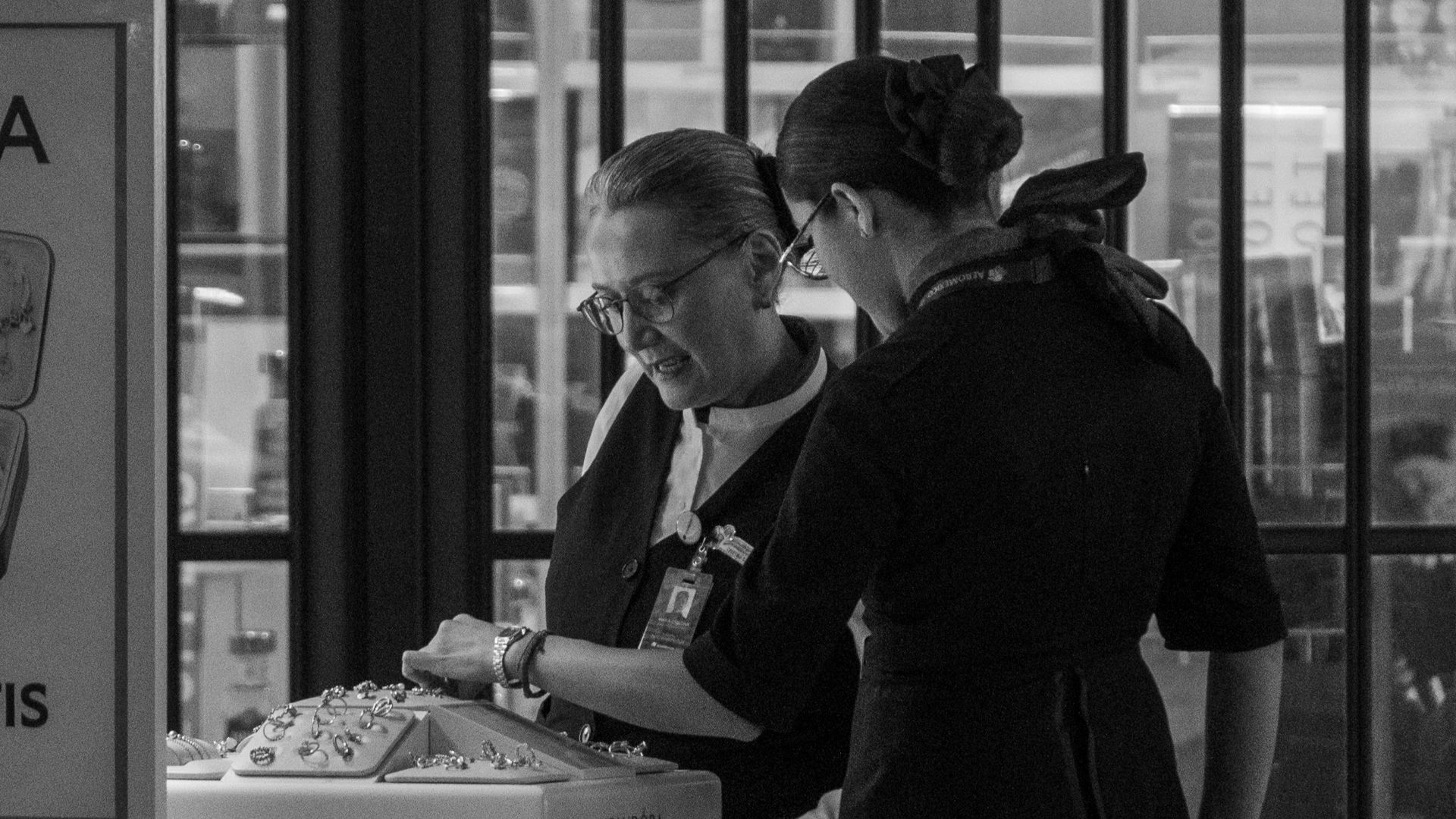 Two airline staff members working at a terminal counter, assisting passengers.