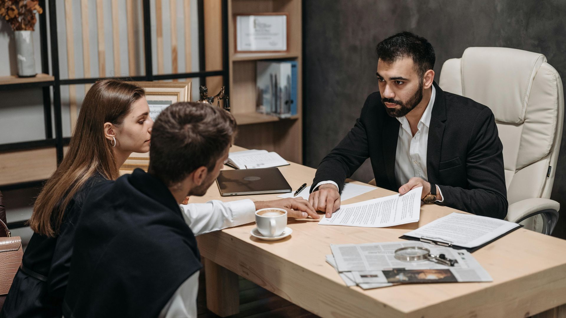 Lawyer discussing legal documents with clients at office desk.