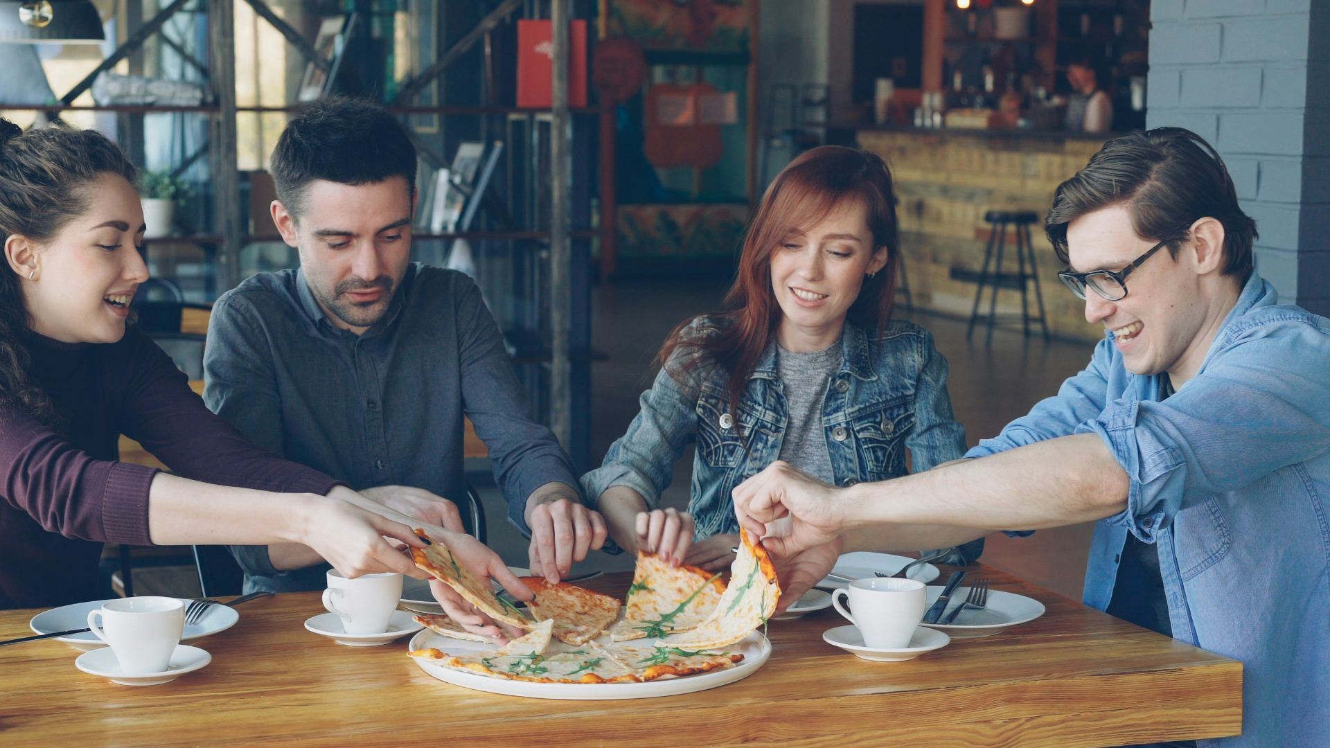 Friends are sharing a pizza at a restaurant.