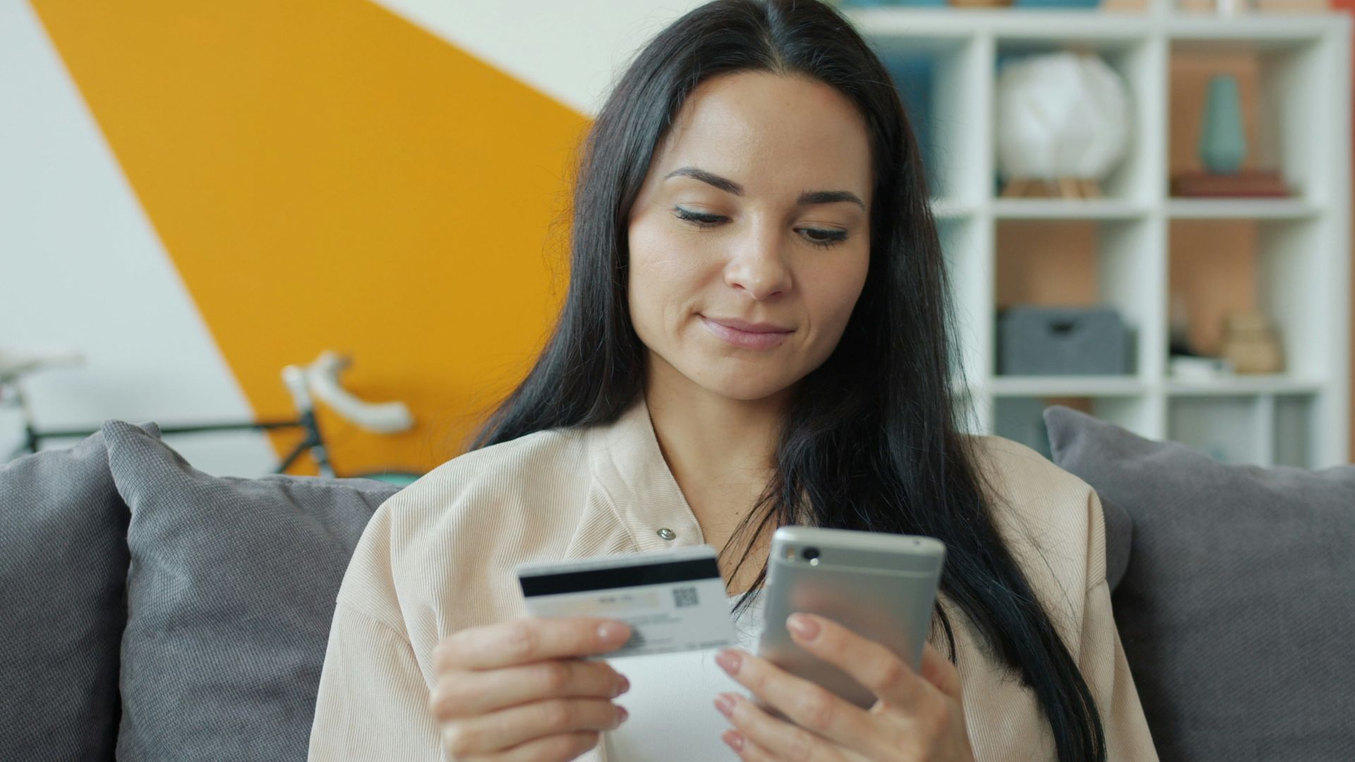 Woman holding credit card and phone for online shopping.