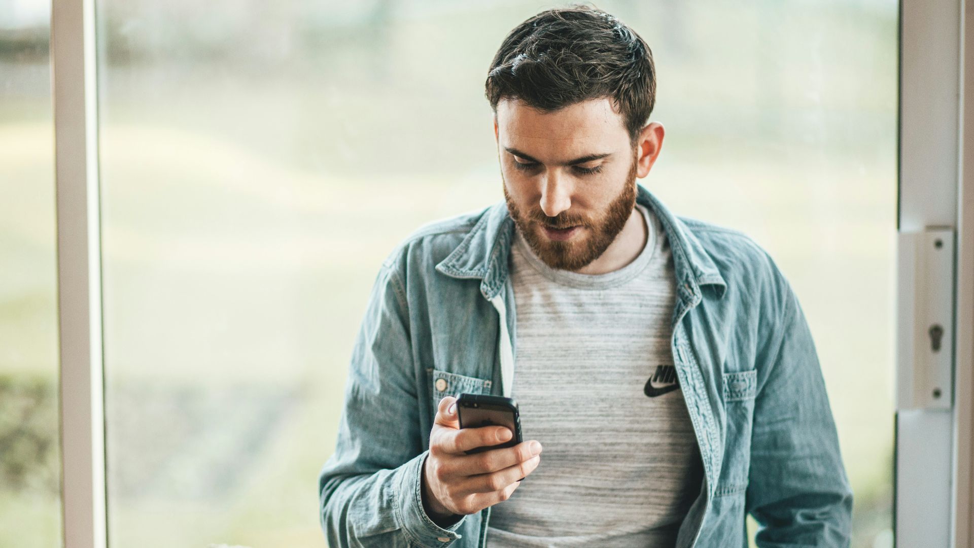 man holding a smartphone near the window