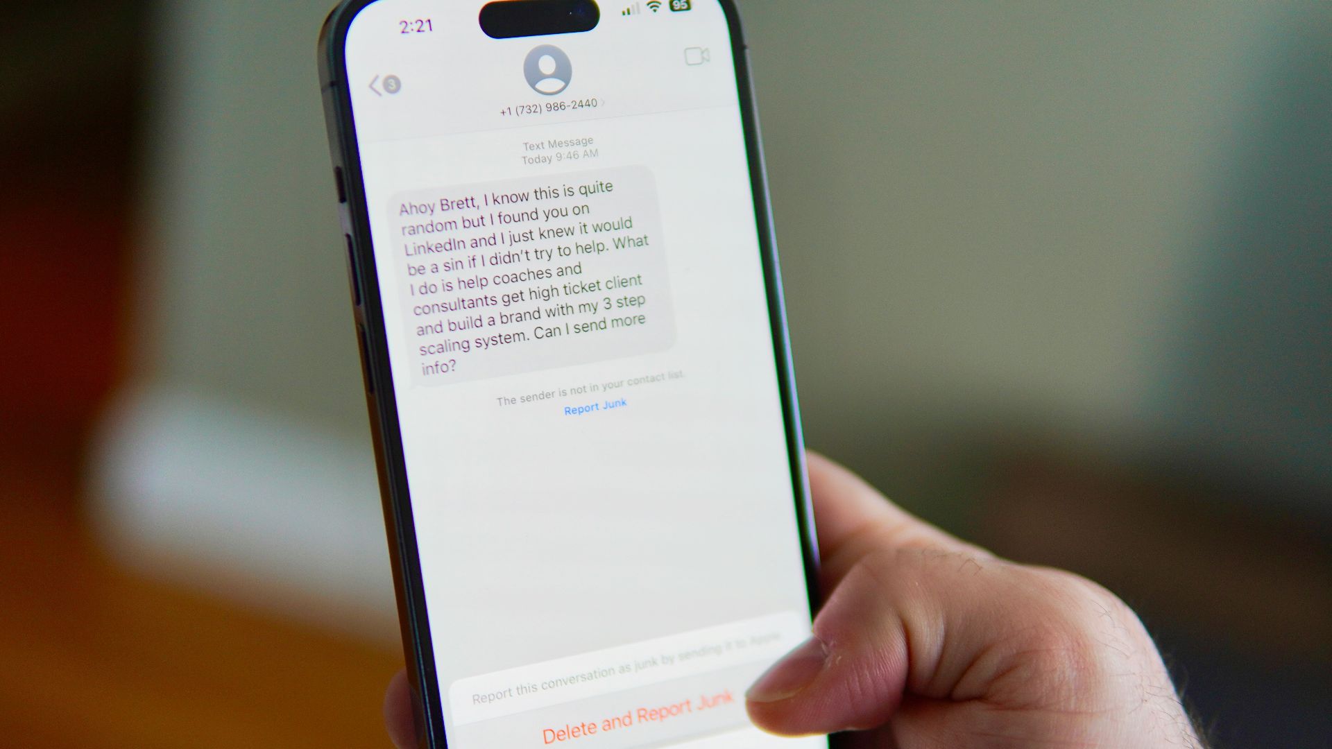 Hand holding a smartphone displaying a text message conversation.