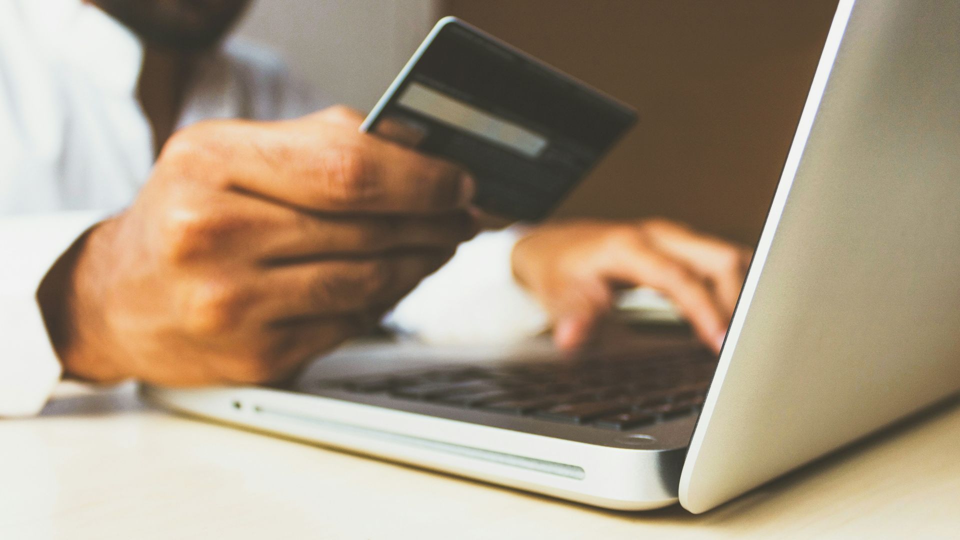 person using laptop computer holding card