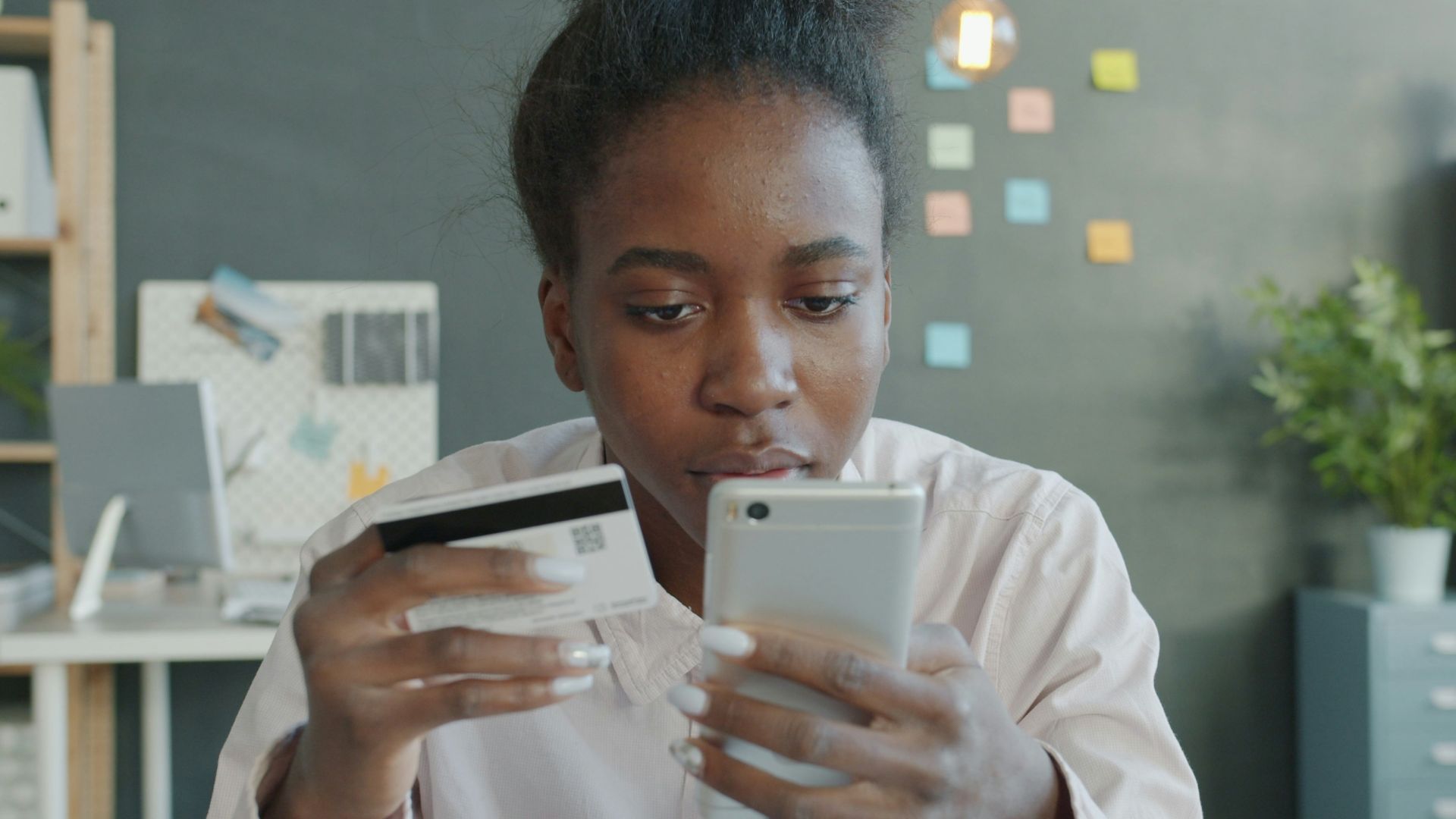 Woman holding credit card and smartphone for online shopping.