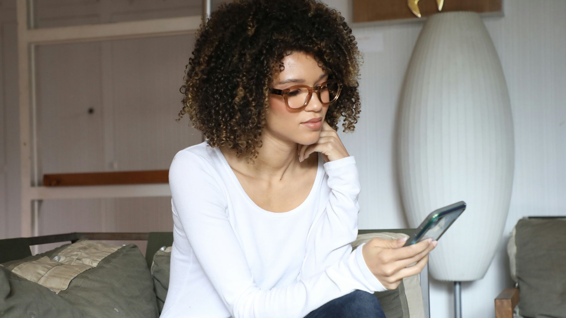 woman in white long sleeve shirt and blue denim jeans sitting on bed