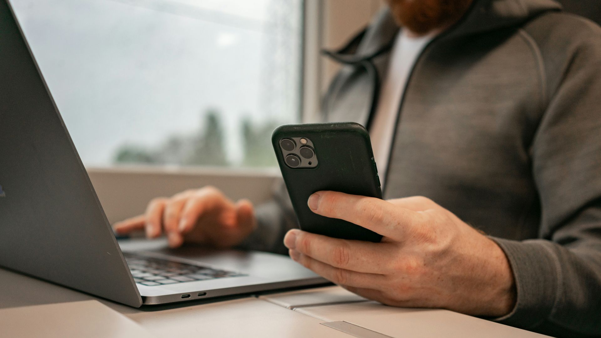 a man sitting in front of a laptop computer holding a cell phone