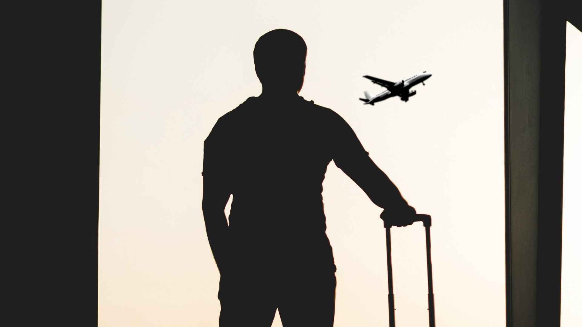 silhouette of man holding luggage inside airport