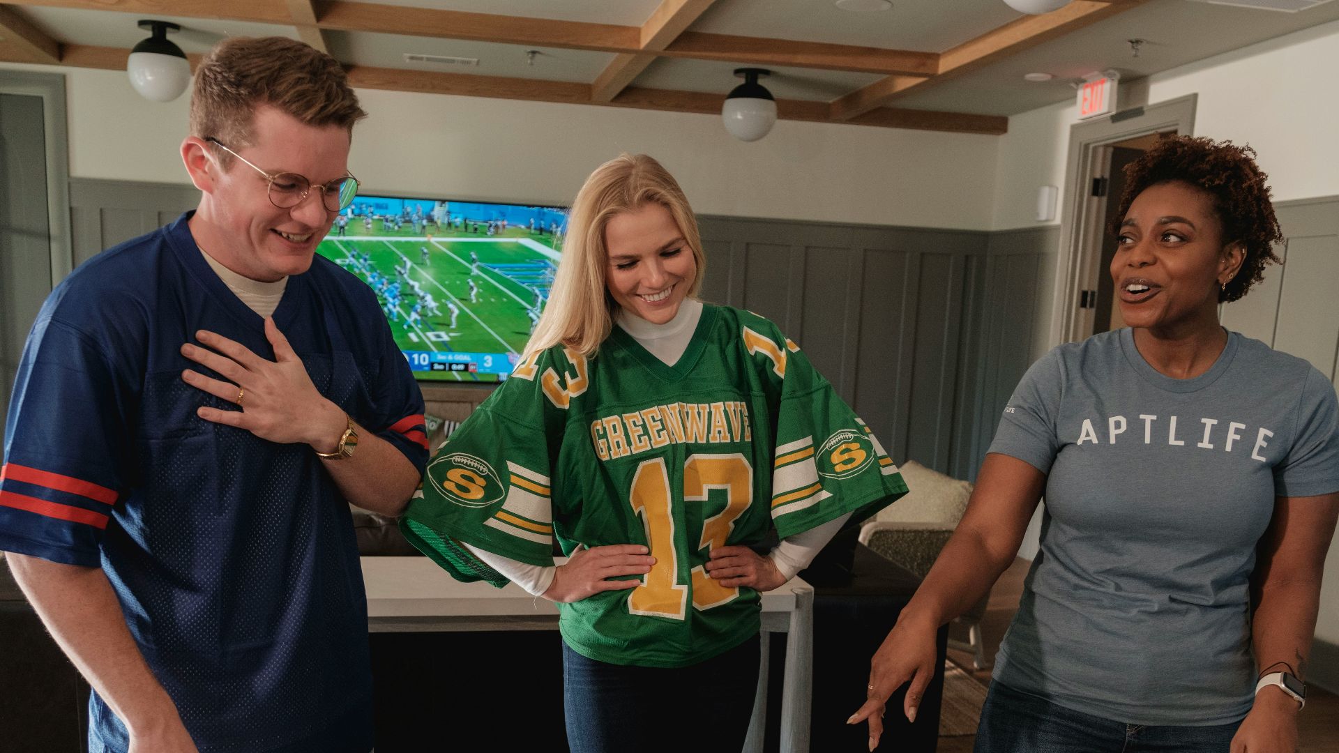 Friends in football jerseys gather around a snack table.