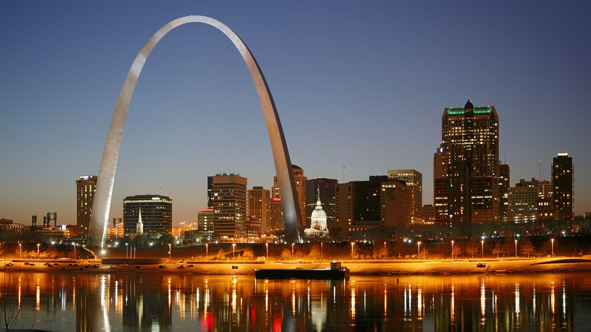 St. Louis on the Mississippi river by night. Jefferson National Expansion Memorial aka. Gateway Arch and Old Courthouse are visible.