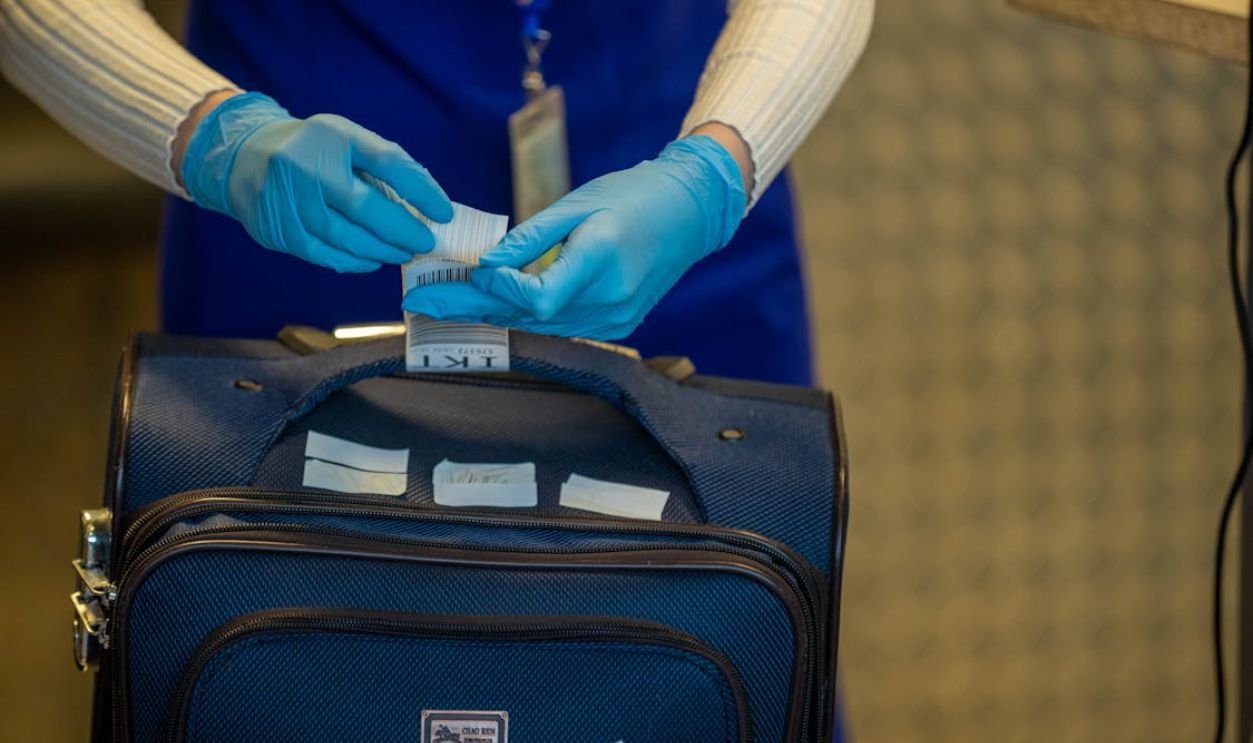 Close-up of airport security process with gloved hands inspecting luggage tags.