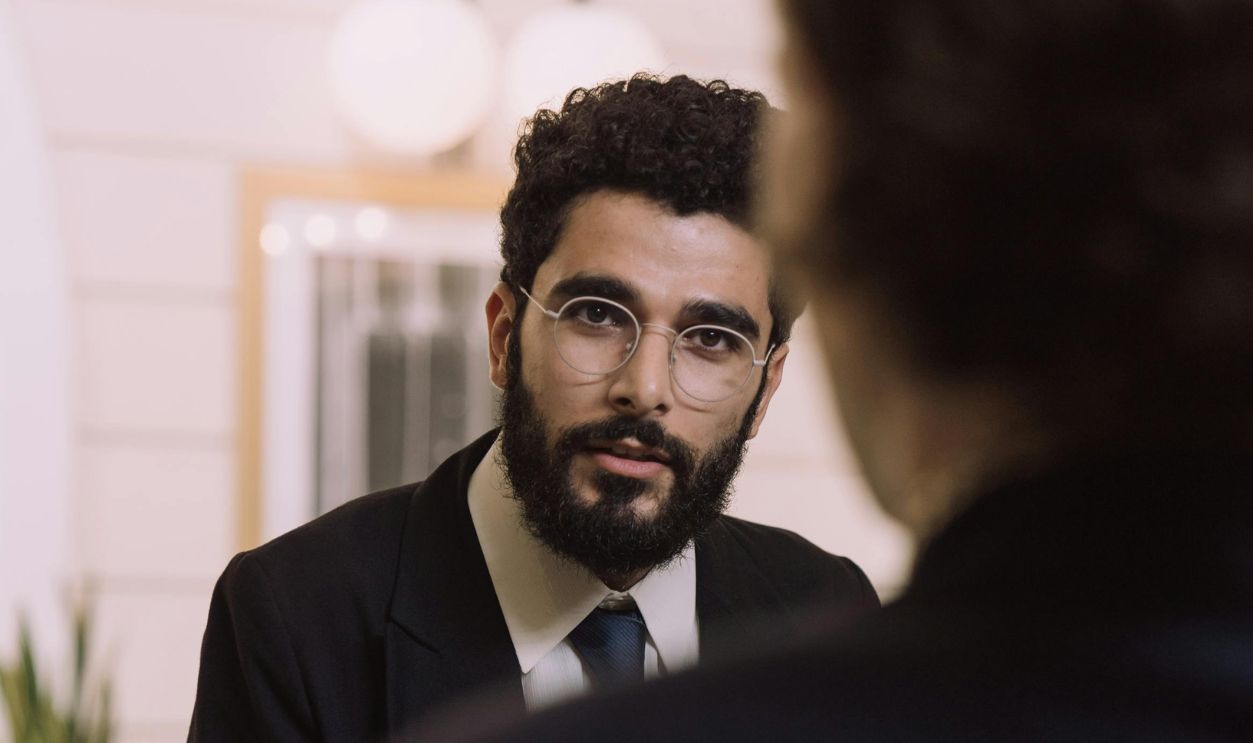 A professional businessman checks in at a hotel reception, engaging with a concierge.
