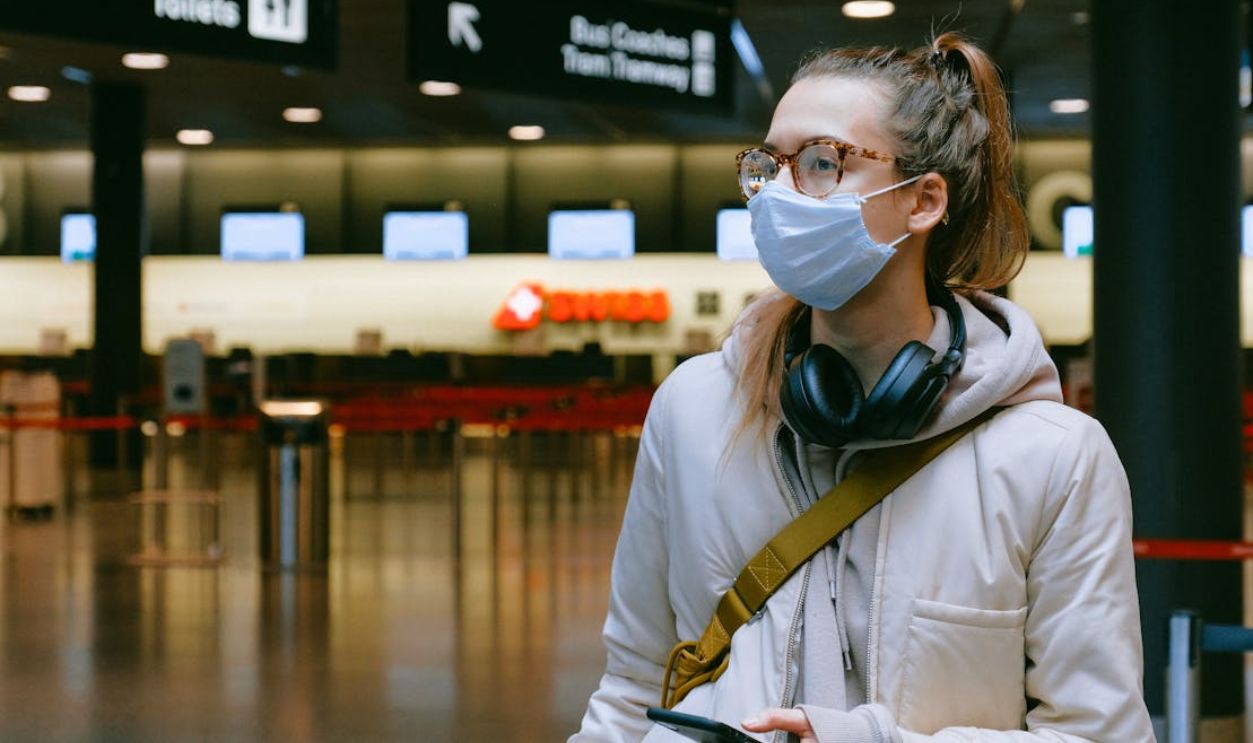 Woman in an airport wearing a face mask for health safety during travel.