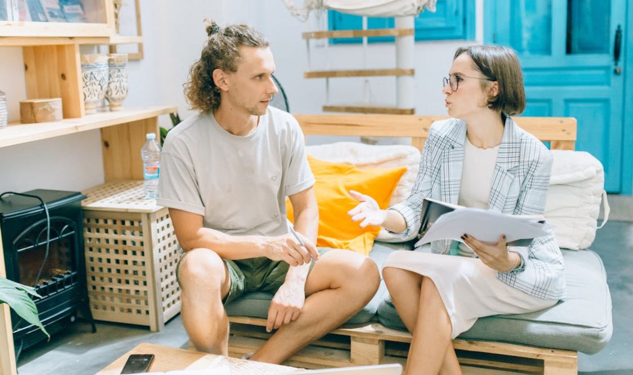A man and woman discussing work in a stylish, bright living room setting.