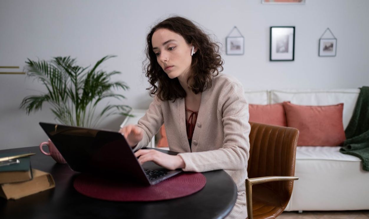 A woman in a cozy home setting working remotely on her laptop, embodying modern digital nomad lifestyle.
