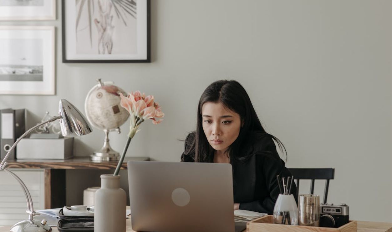 A woman concentrates on her laptop in a stylish home office setup with elegant decor.