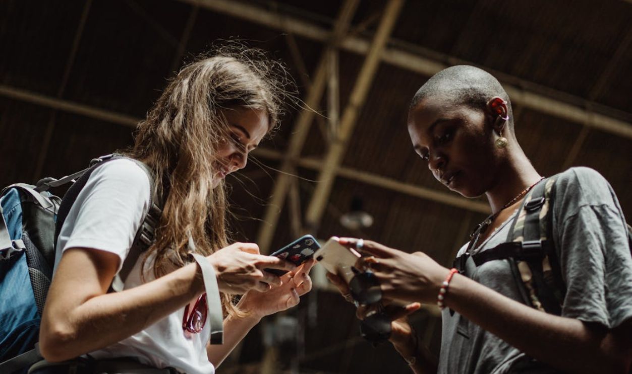 Two women are engrossed in their phones, capturing the essence of modern travel and connectivity.