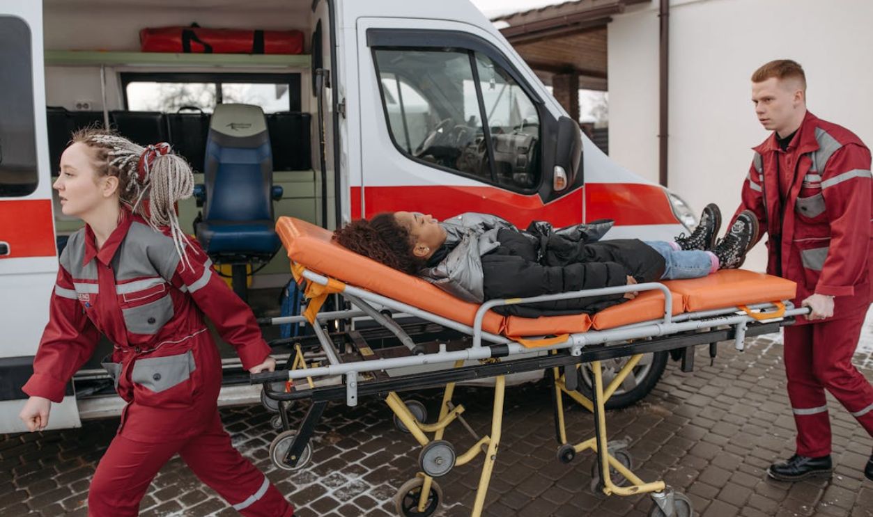 EMTs assist a patient on a stretcher into an ambulance, highlighting emergency response.