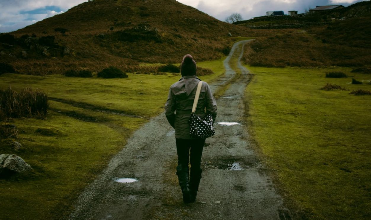 Person walking on a scenic countryside trail, embracing solitude and nature.